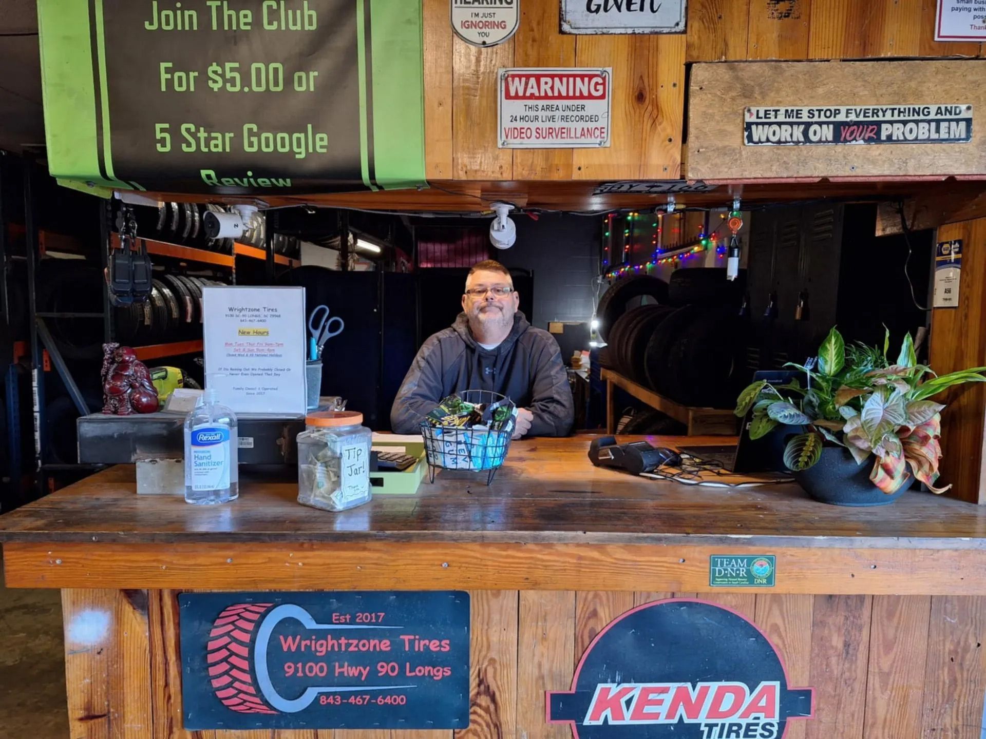 A man is sitting at a counter in a tire shop.
