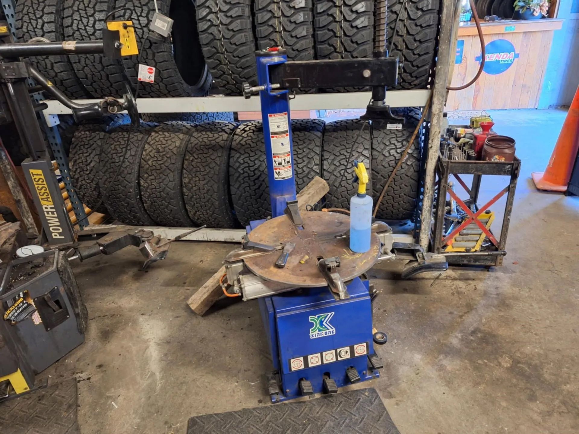 A tire changer is sitting in a garage next to a stack of tires.