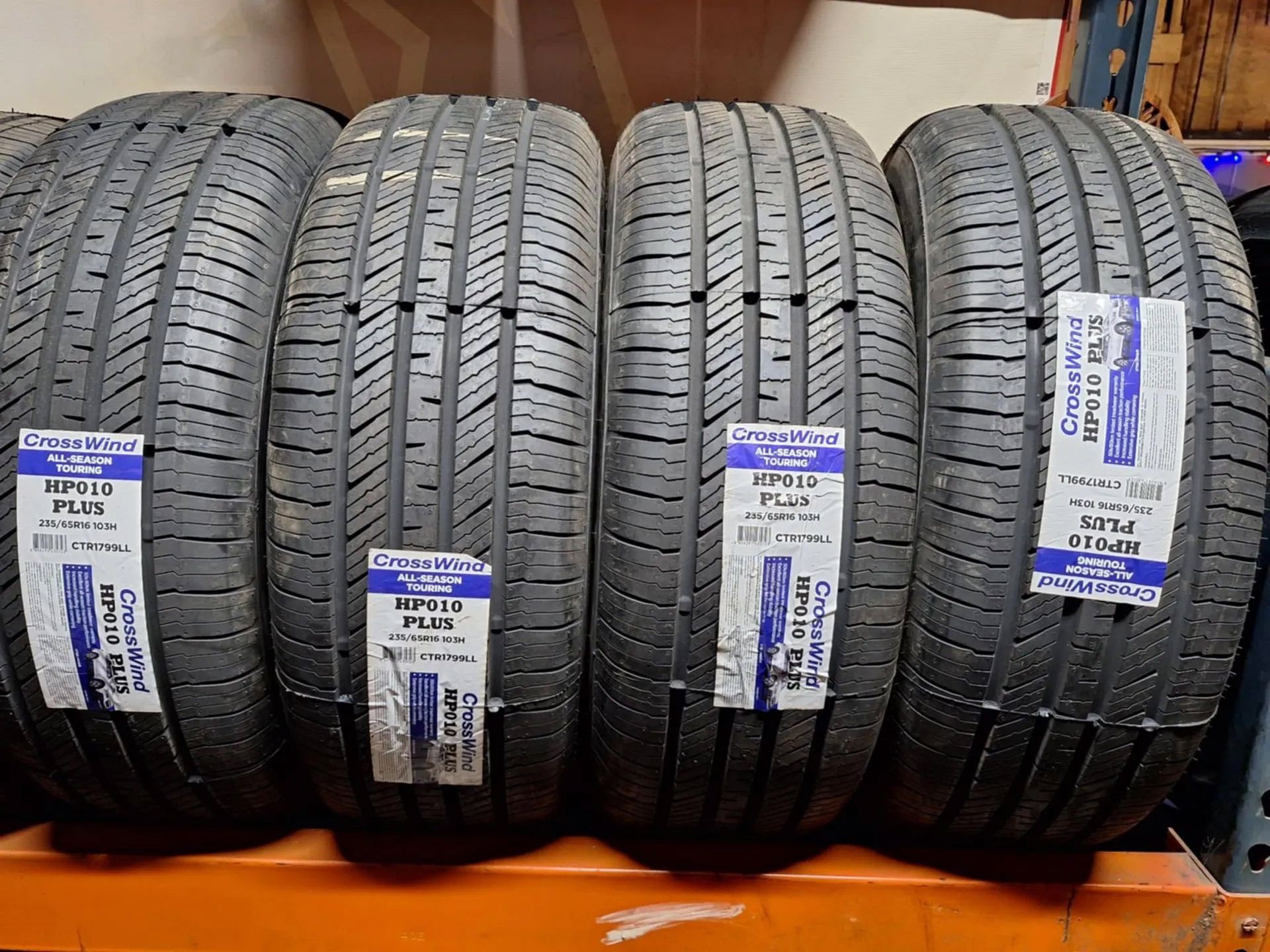 Four tires are lined up on a shelf with labels on them.