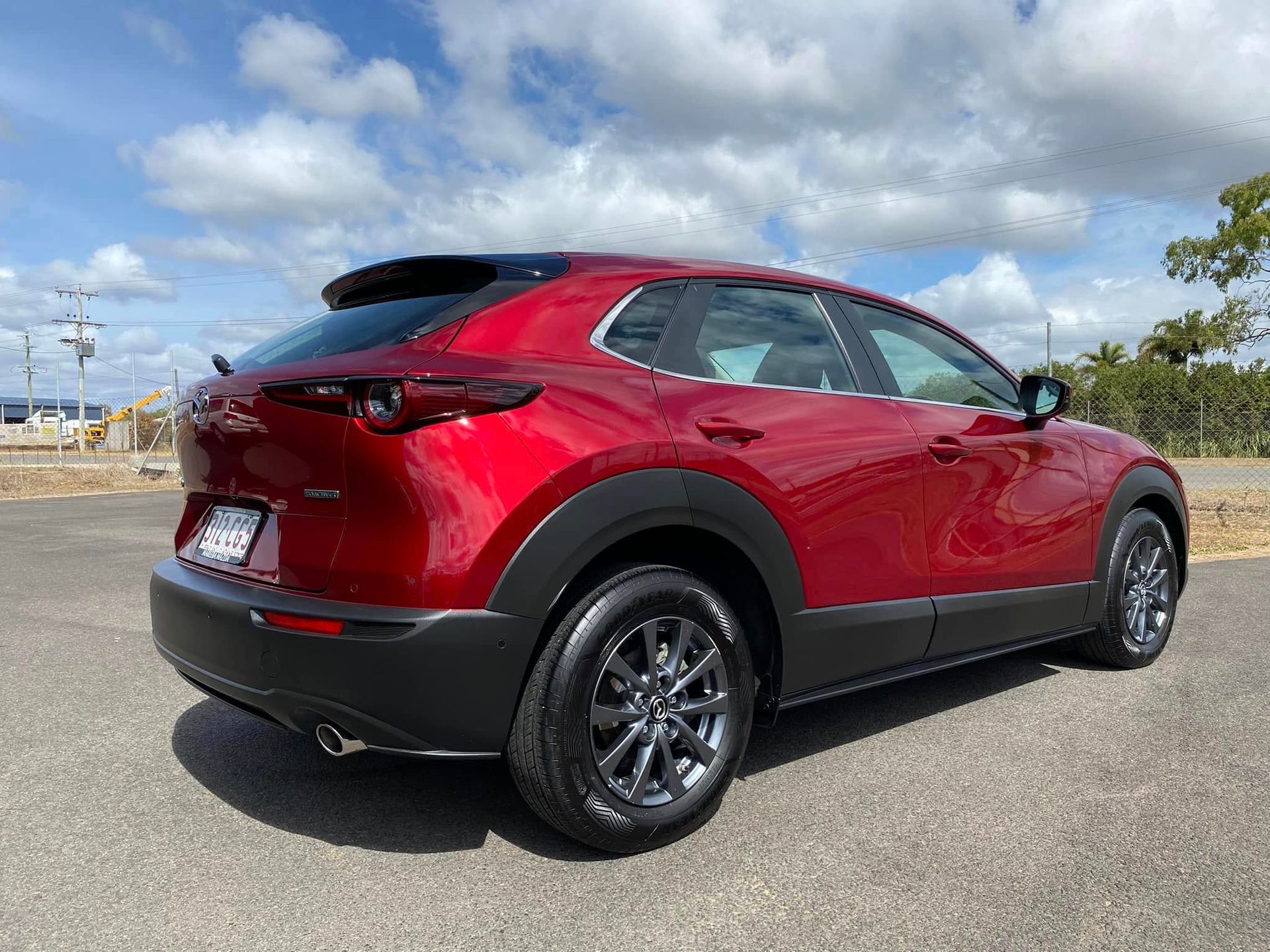 Red SUV parked on asphalt under a cloudy sky, rear three-quarter view — Beclean Auto Detailing in Mareeba, QLD