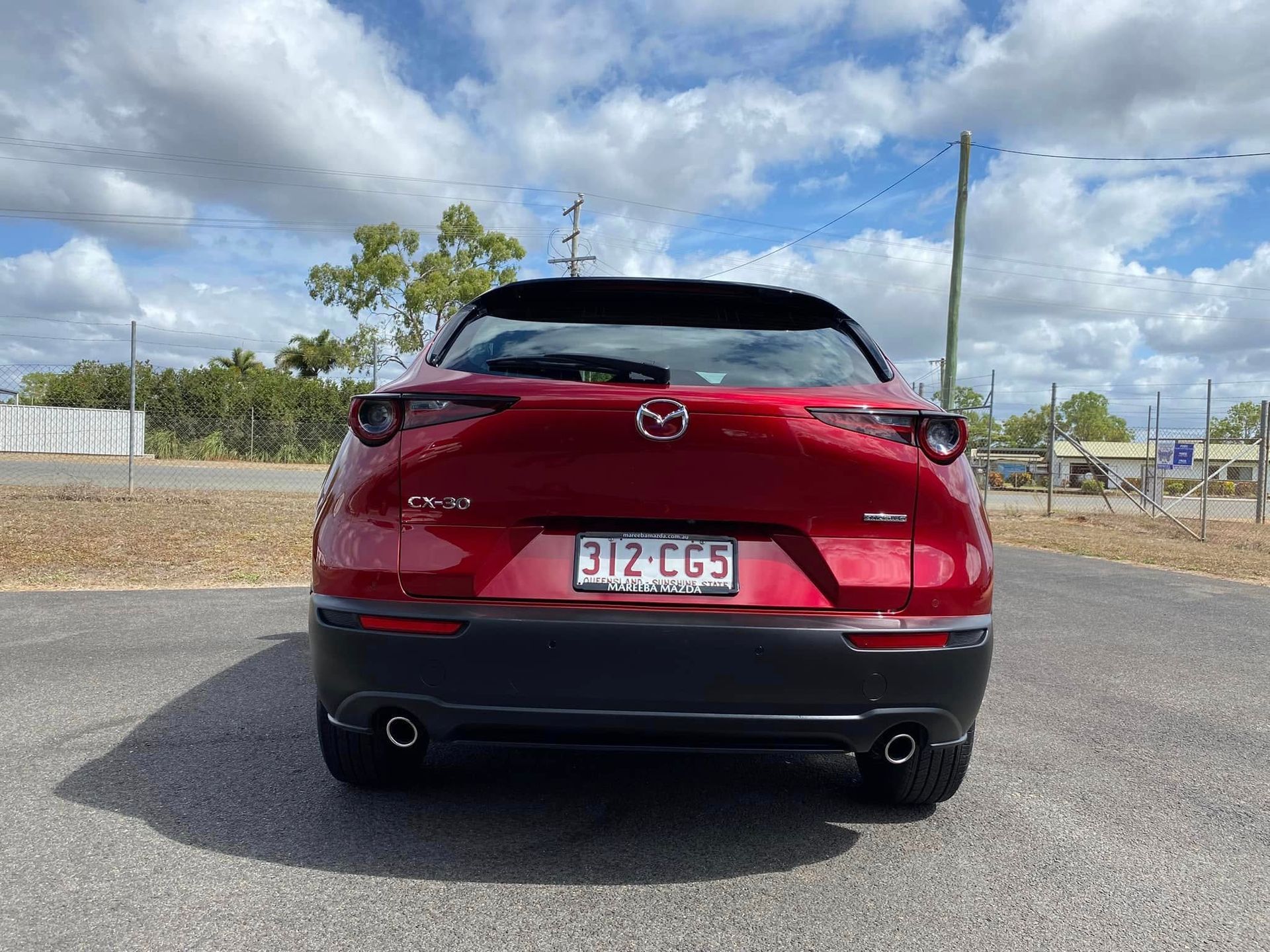 Rear view of a red Mazda SUV parked on a road under a partly cloudy sky — Beclean Auto Detailing in Mareeba, QLD