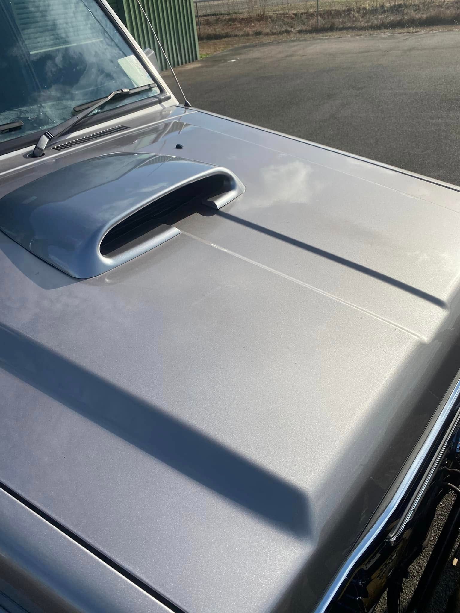 Close-Up of A Silver Car Hood with A Raised Black Air Scoop in Sunlight — Beclean Auto Detailing in Mareeba, QLD