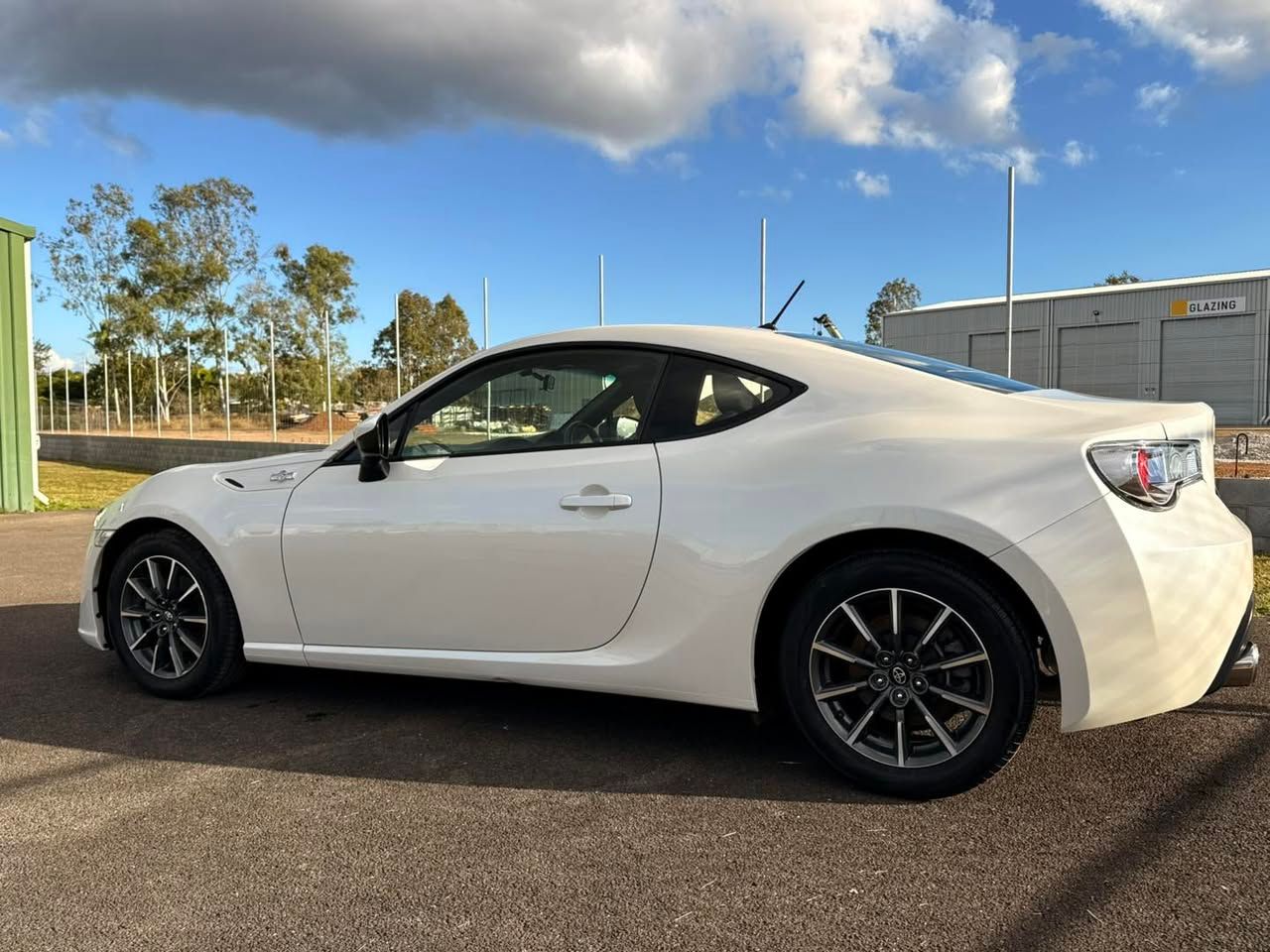 White sports coupe parked outdoors on asphalt under a partly cloudy sky, side view — Beclean Auto Detailing in Mareeba, QLD