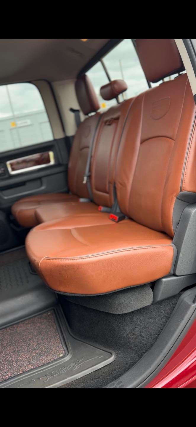 The interior back seat of a truck, featuring brown leather upholstery and a black carpeted floor.