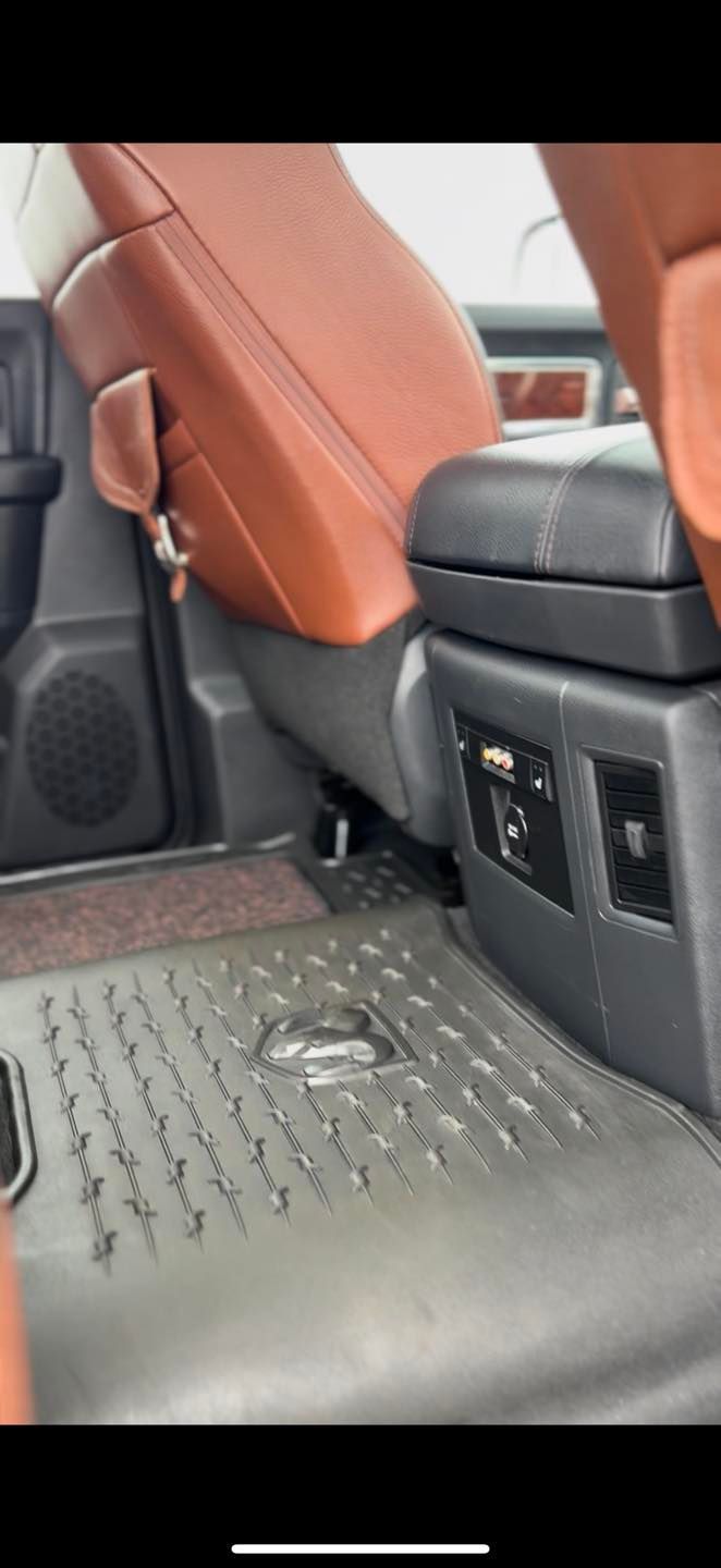 Interior view of a vehicle's back seat area, showing brown leather seats and a black center console with power ports.