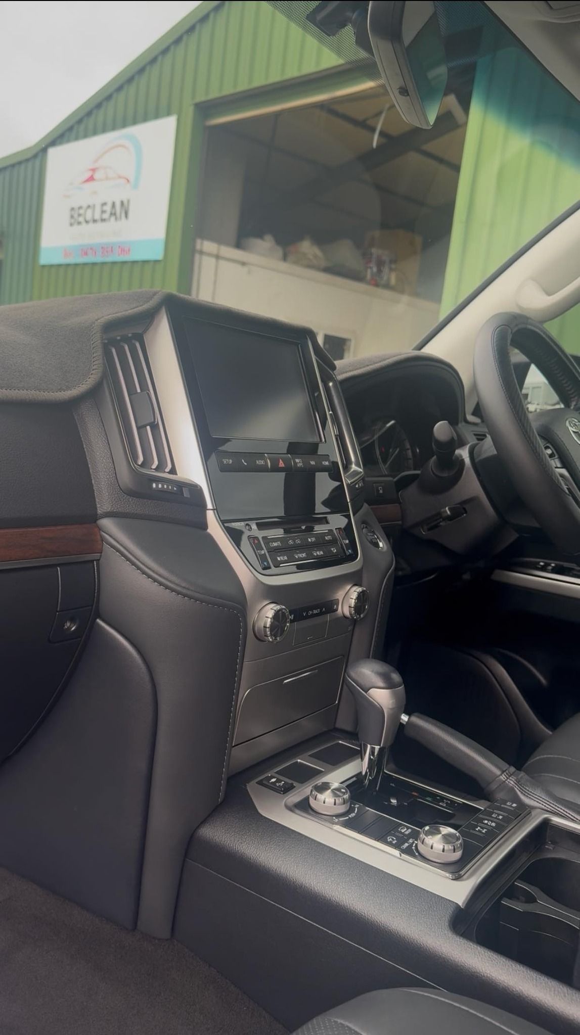A close-up of a modern vehicle interior featuring a large vertical touchscreen display and a center console gear shifter.