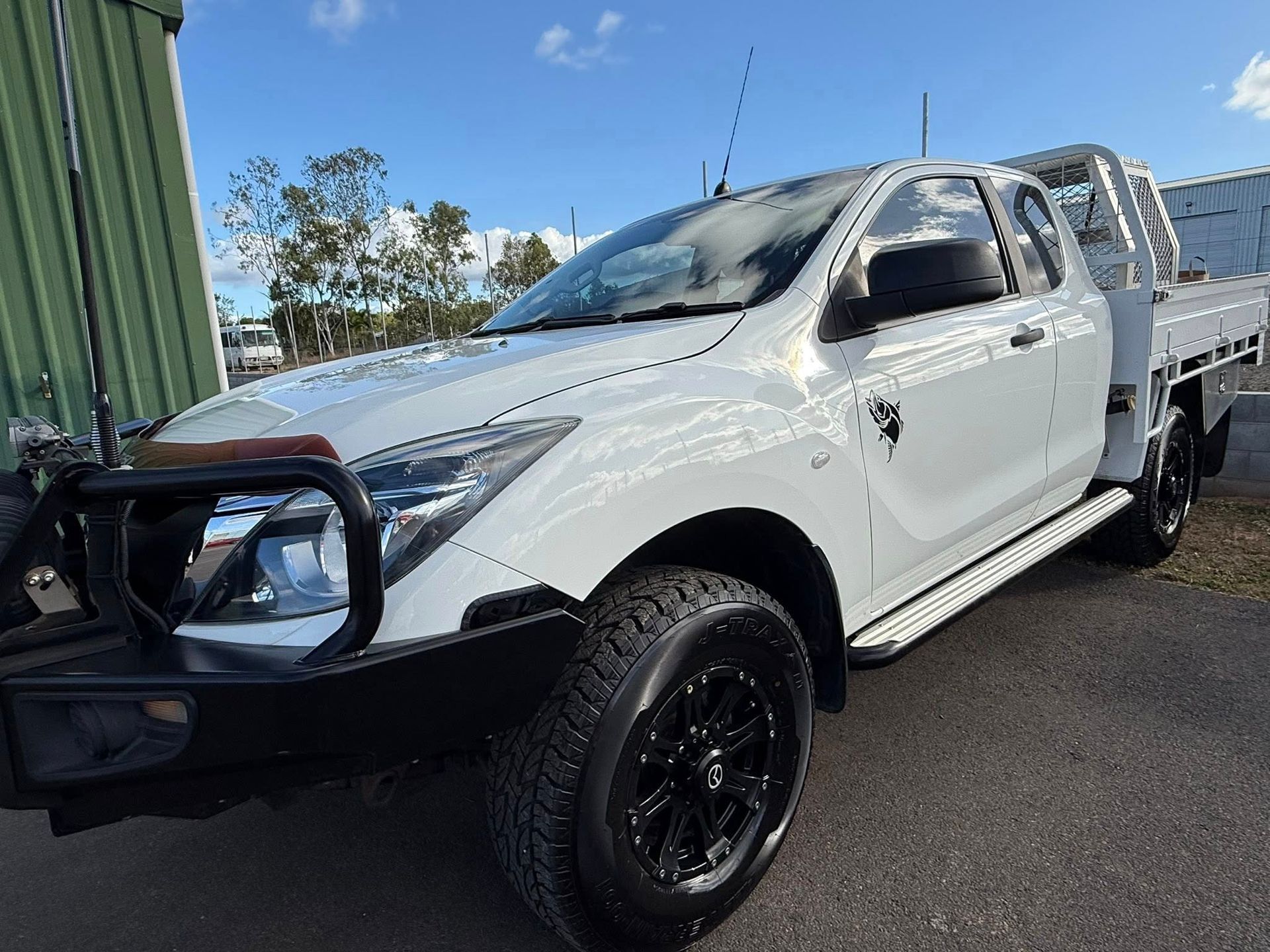 White Isuzu D-Max dual-cab utility vehicle with a black bull bar and black alloy wheels parked on an outdoor lot.