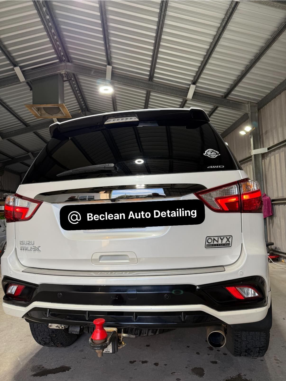 White SUV at Baclen Auto Detailing garage, rear view with red tow hook and chrome exhaust — Beclean Auto Detailing in Mareeba, QLD