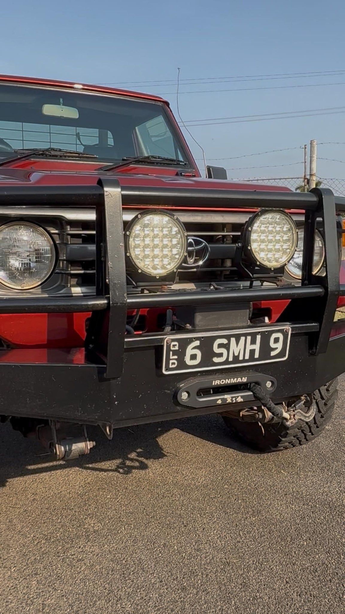 Front view of a red off-road vehicle with a black bull bar and twin headlights on a gravel surface — Beclean Auto Detailing in Mareeba, QLD