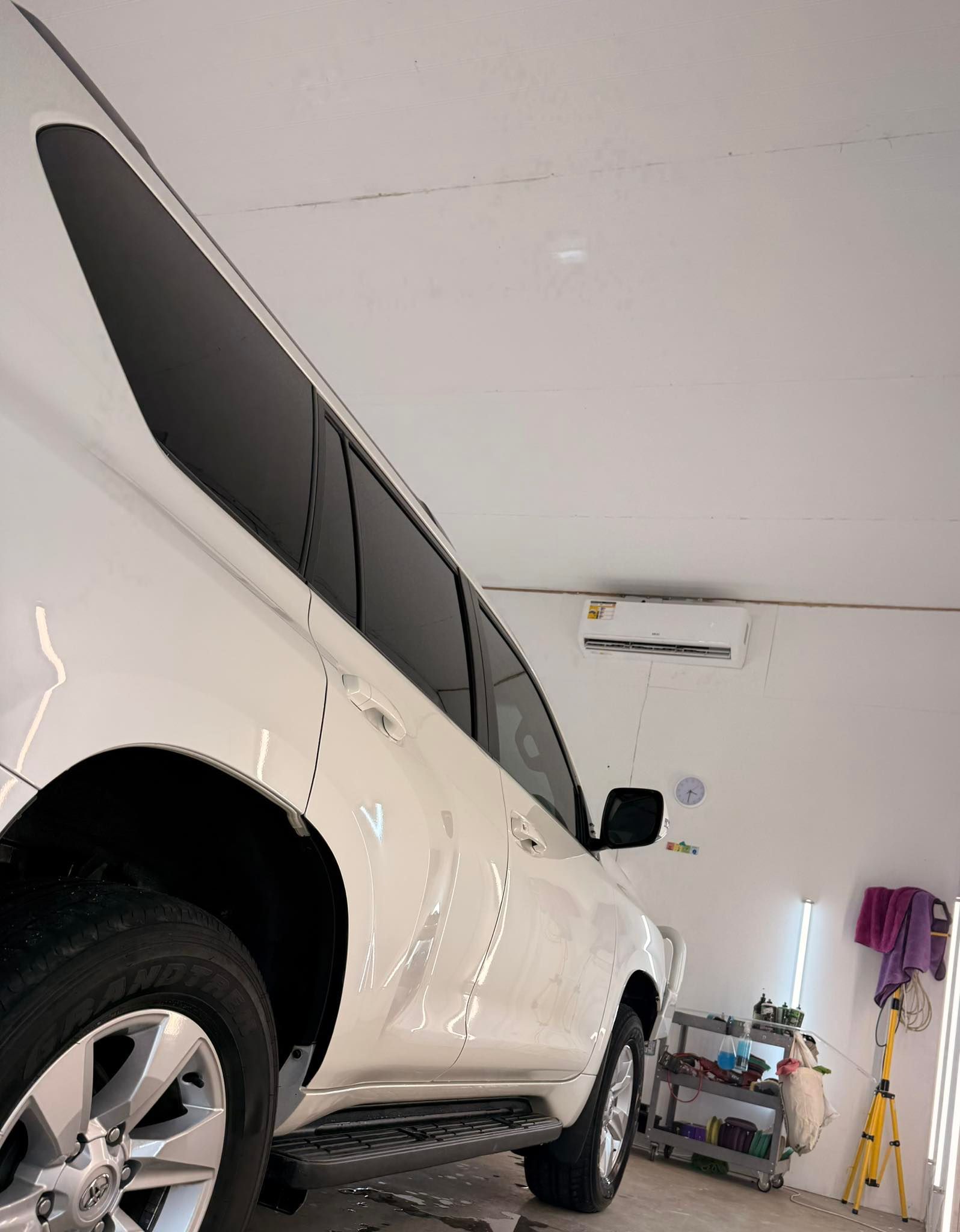 White SUV parked in a garage, viewed from the rear side with storage items and a ladder in the background — Beclean Auto Detailing in Mareeba, QLD