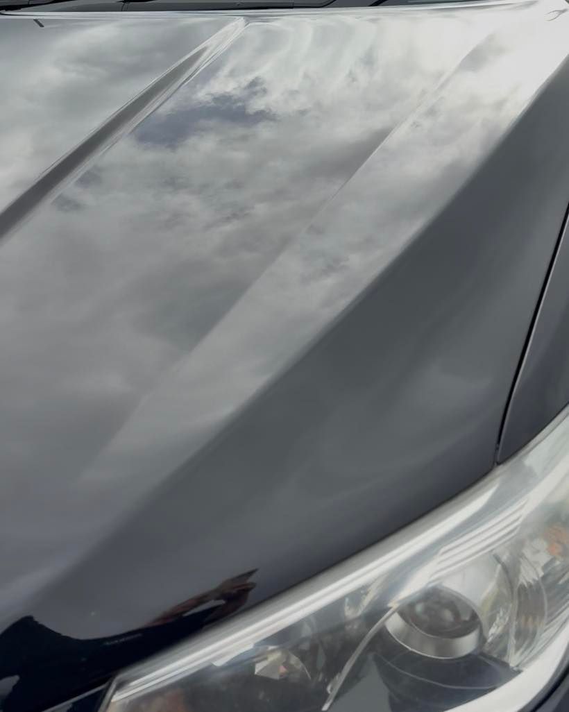 Close-Up of A Black Car Hood and Headlight with Cloudy Reflections on The Paint — Beclean Auto Detailing in Mareeba, QLD