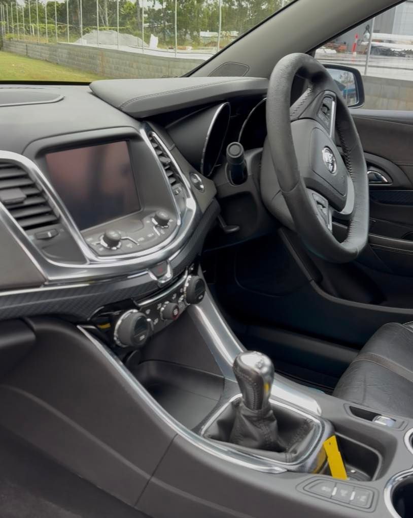 Car interior with black dashboard, steering wheel, and manual gear shift in a parked vehicle — Beclean Auto Detailing in Mareeba, QLD