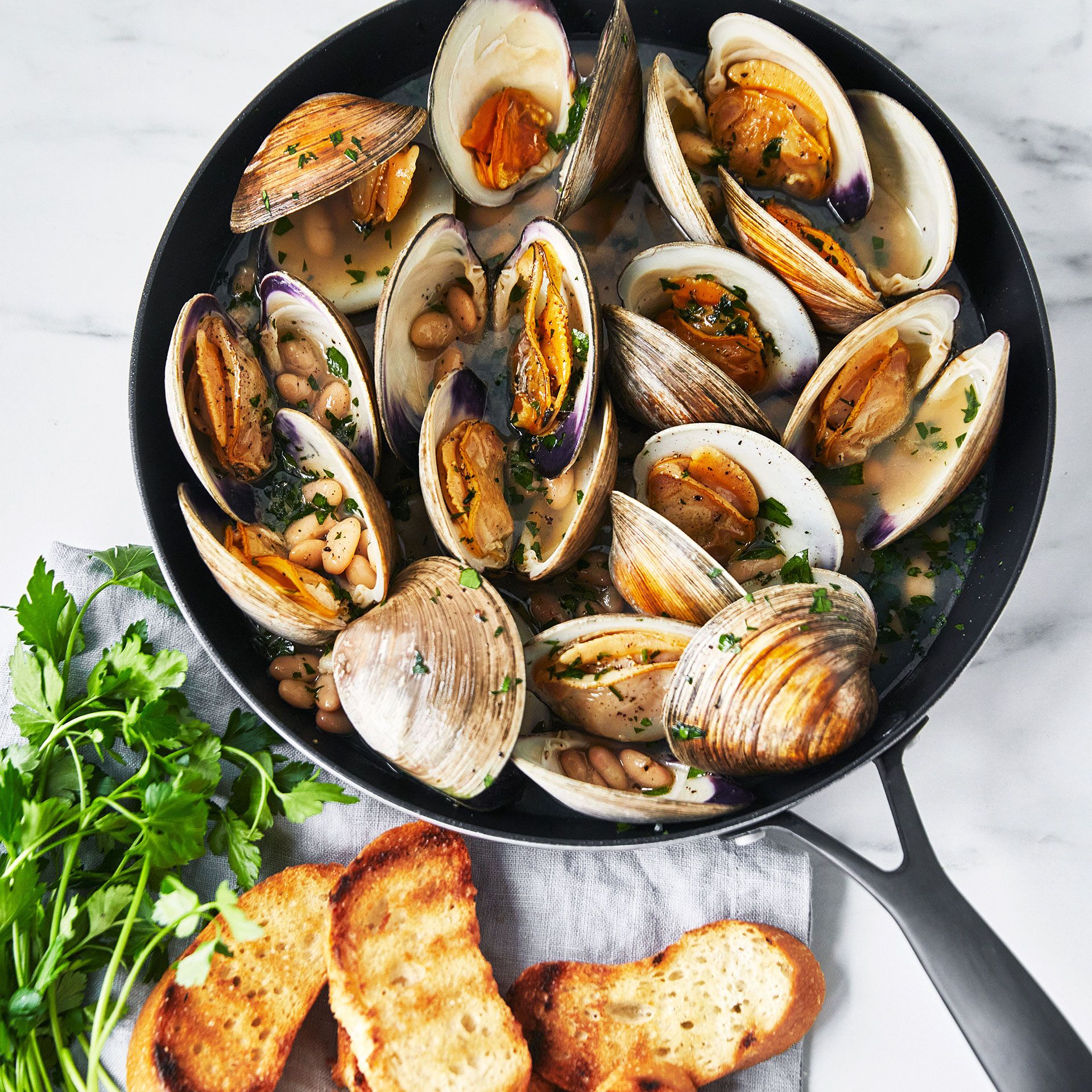 A pan filled with clams and bread on a table.