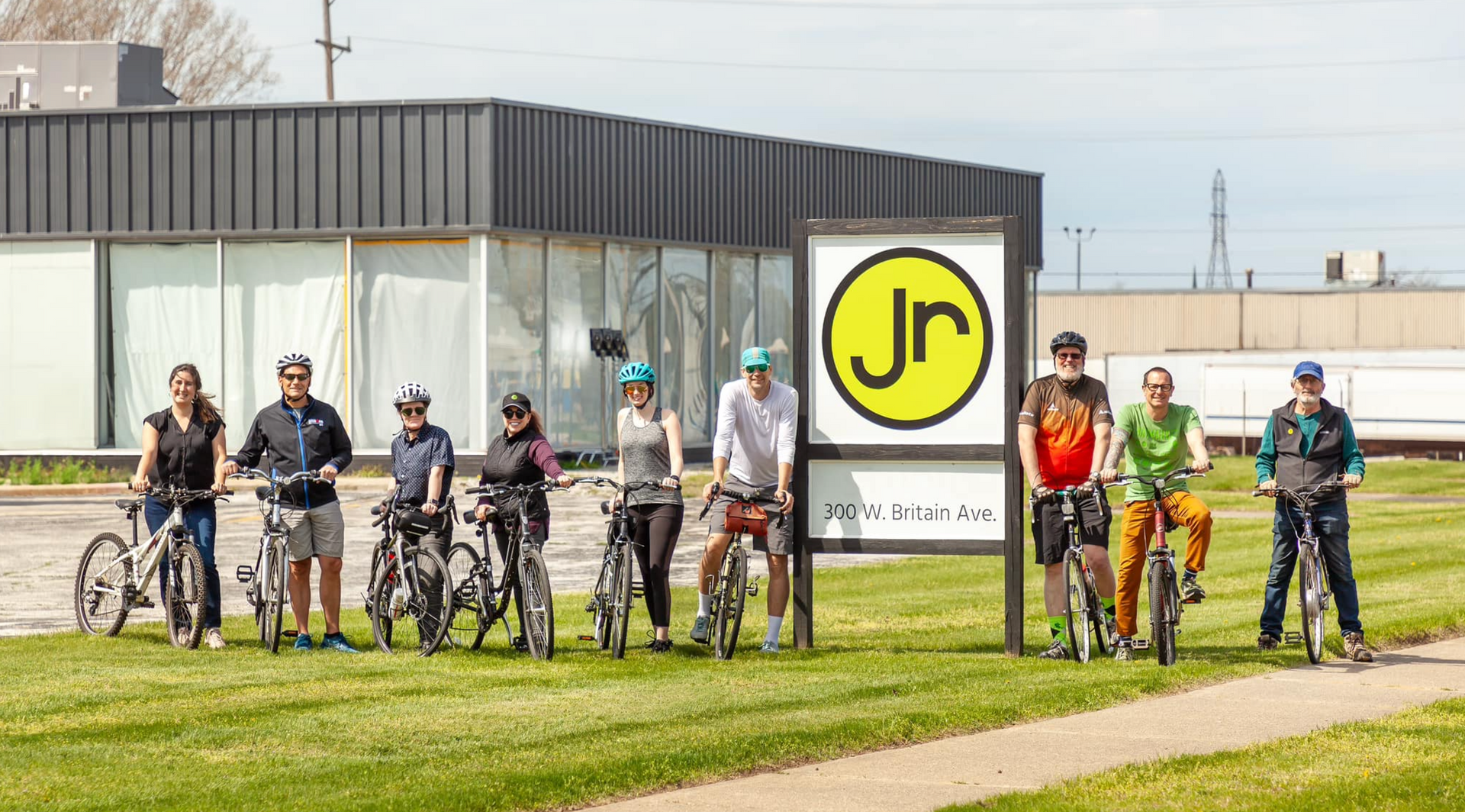 A group of people are riding bicycles in front of a JR building.