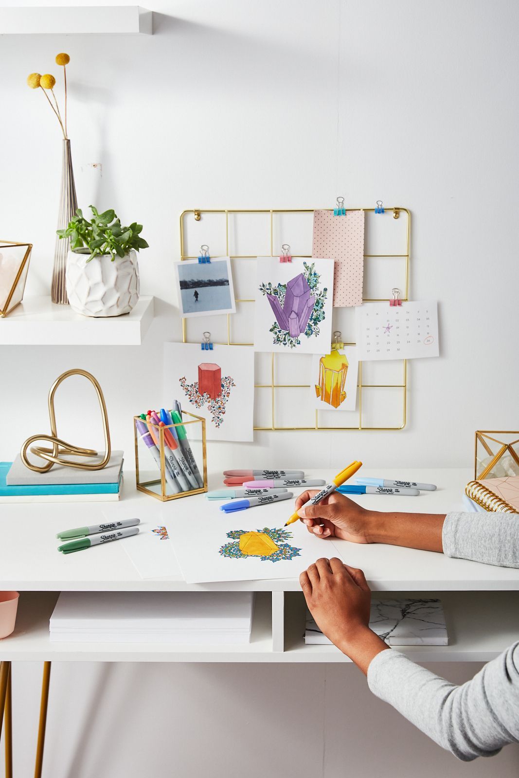 A person is sitting at a desk drawing with Sharpie markers.
