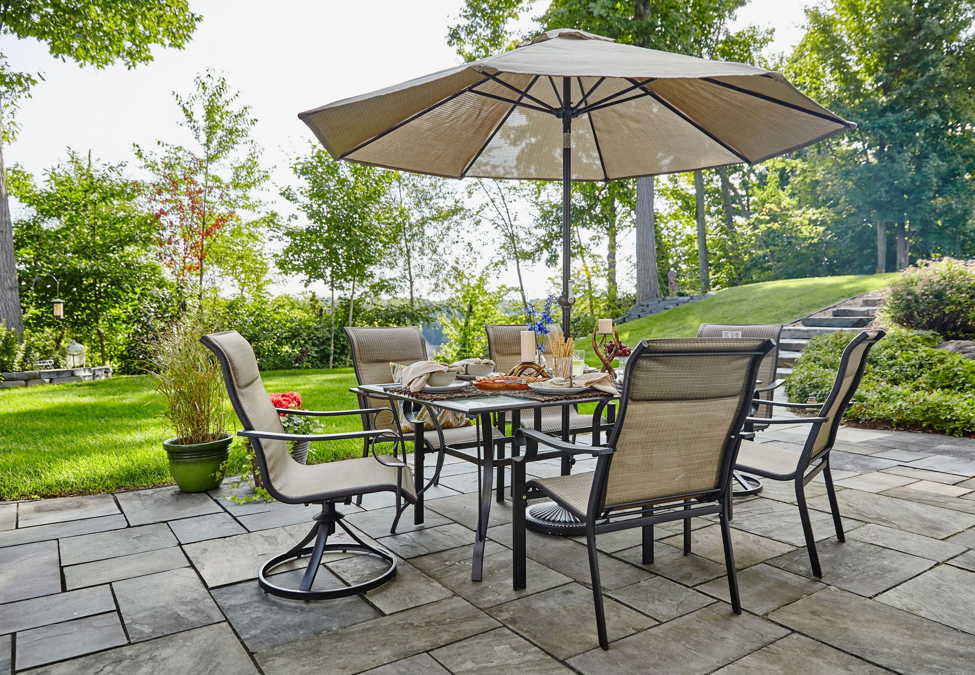 A patio with a table and chairs and an umbrella in a beautiful backyard