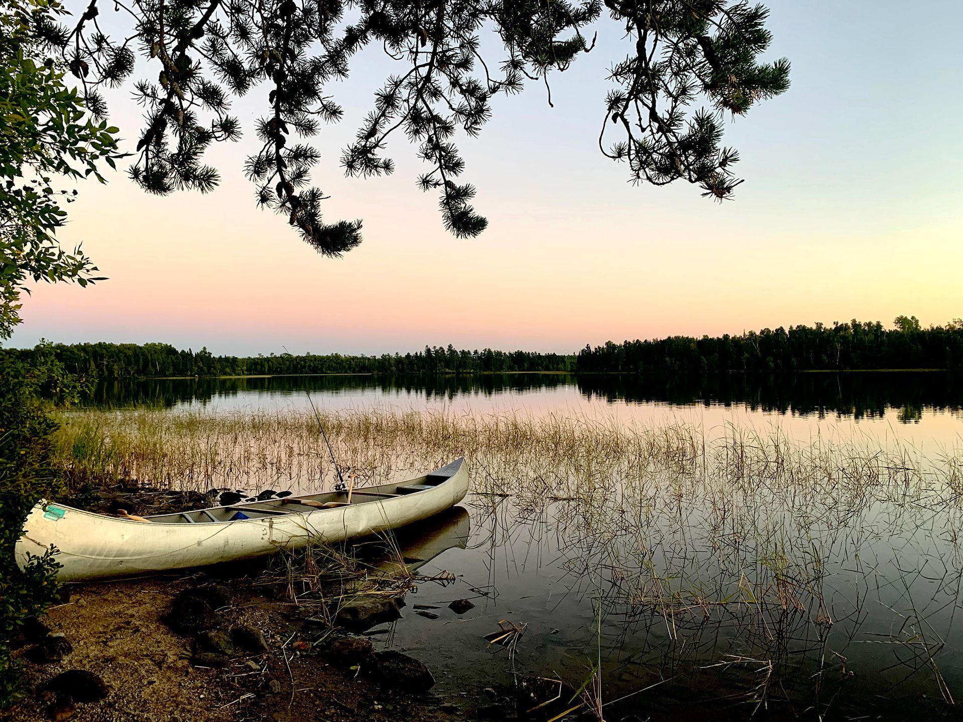 A white canoe sits on the shore of a beautiful  lake