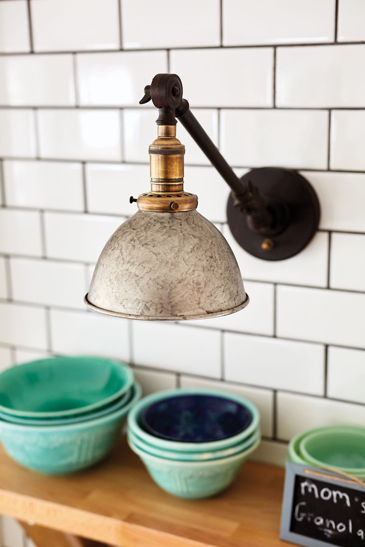 A light is hanging from a wall next to a chalkboard that says mom 's granola