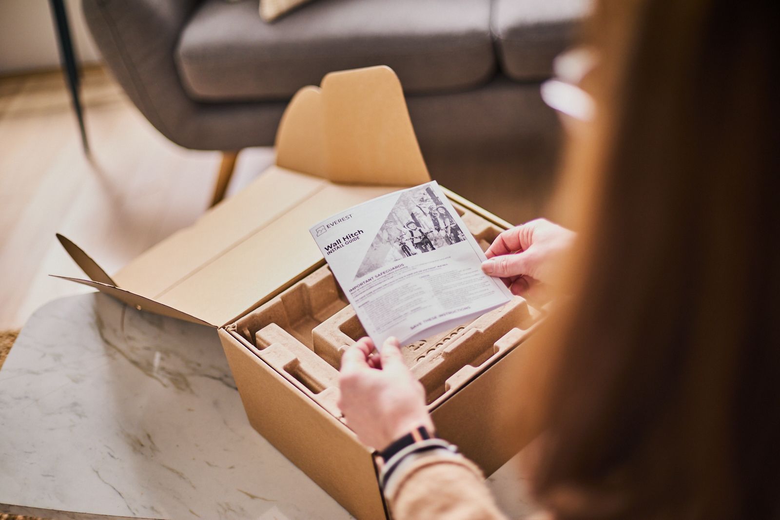 A woman is holding a piece of paper in front of a cardboard box.