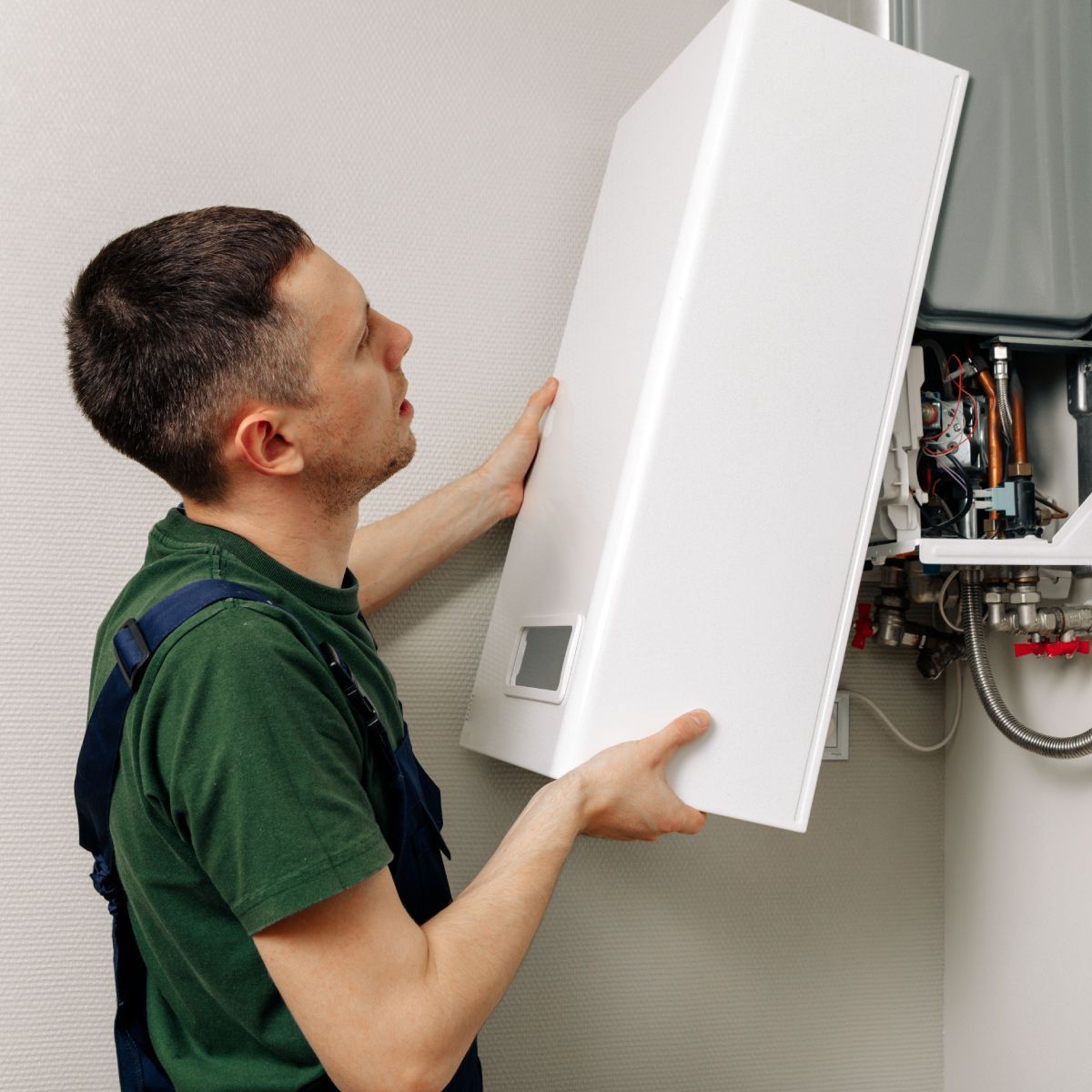 A man is fixing a boiler in a bathroom.