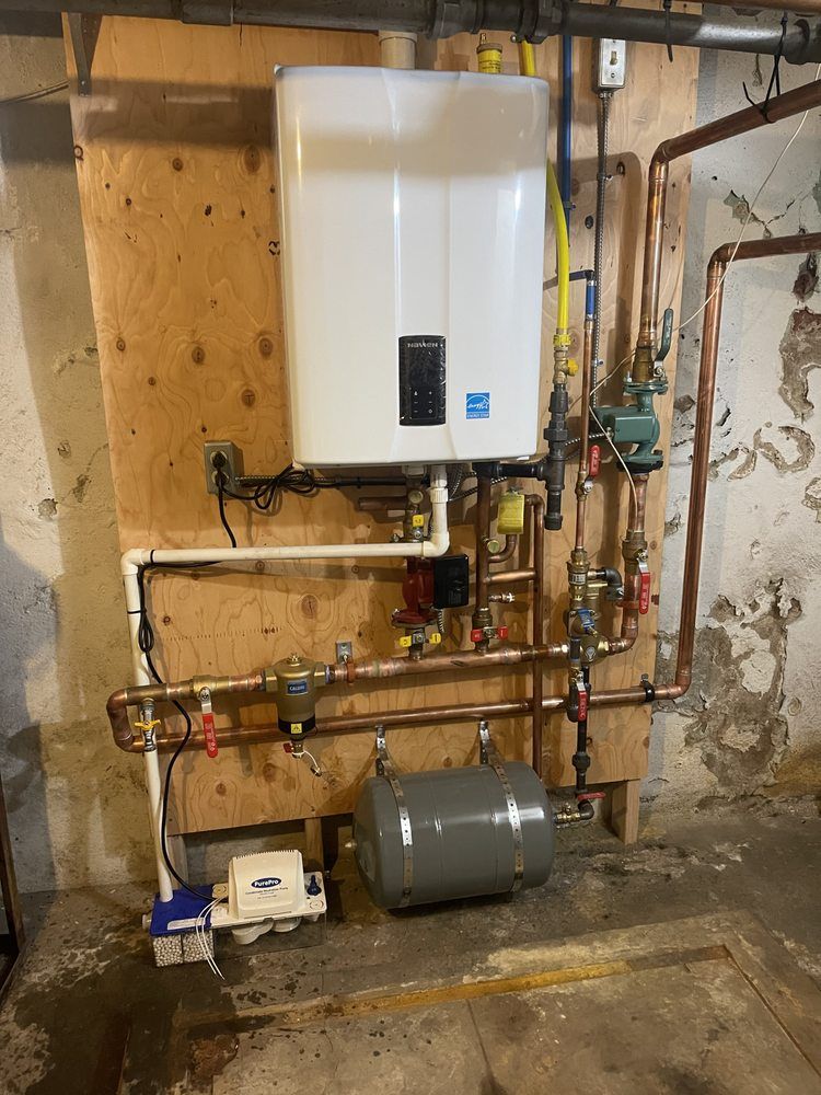 A white water heater is sitting on a wooden wall next to copper pipes.