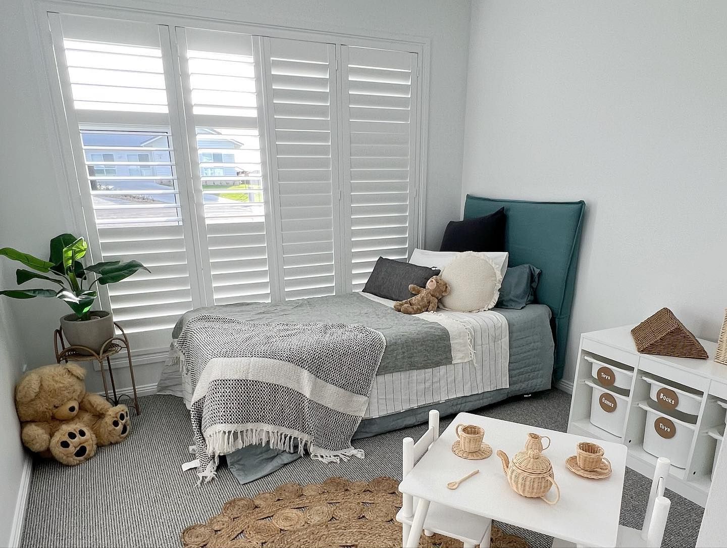 A bedroom with a bed , table , chairs and shutters.