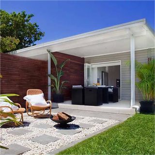 A patio with rocking chairs and a fire pit in front of a house