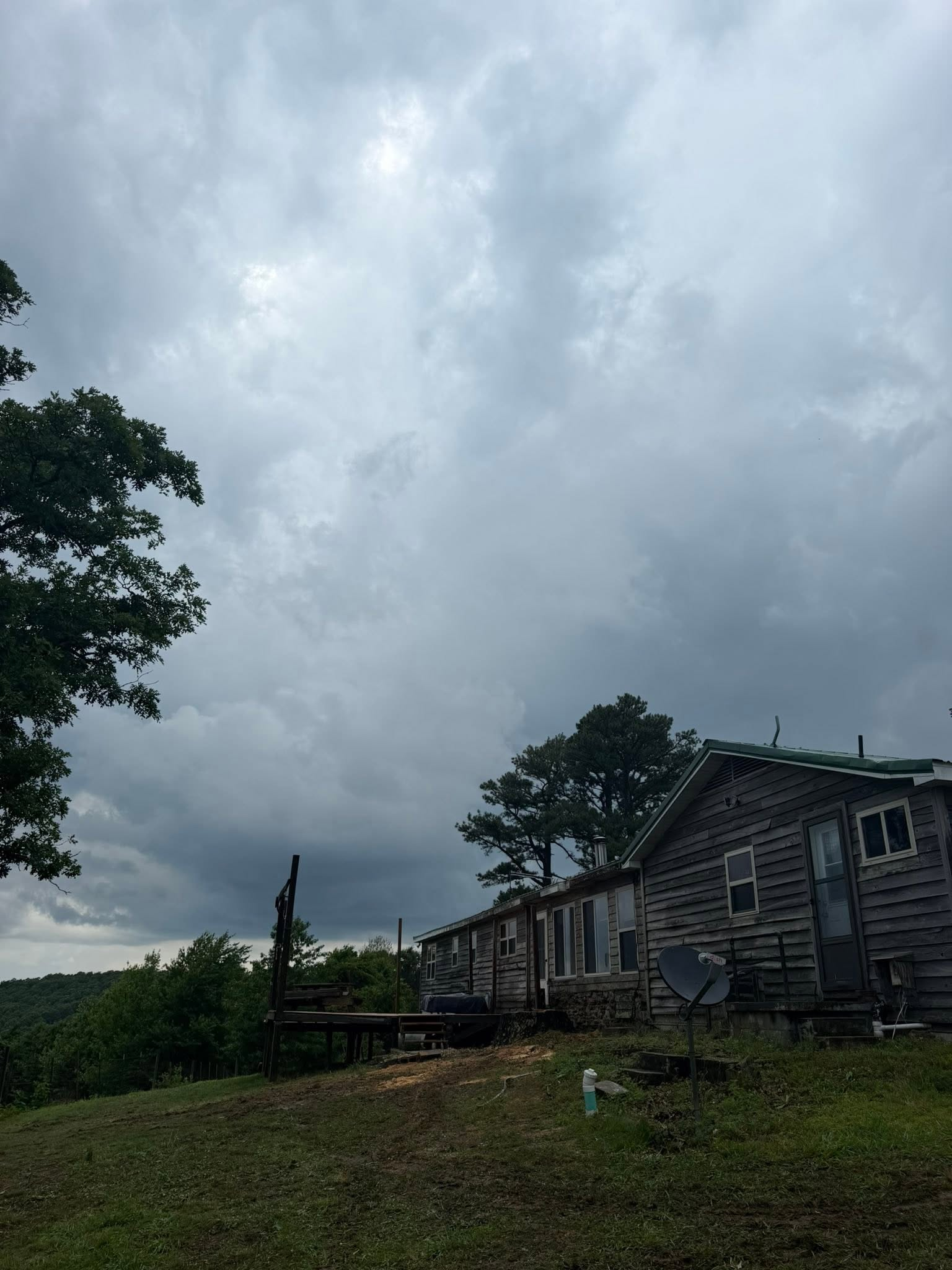 Rustic wooden cabins on a grassy hillside under a dark, cloudy sky