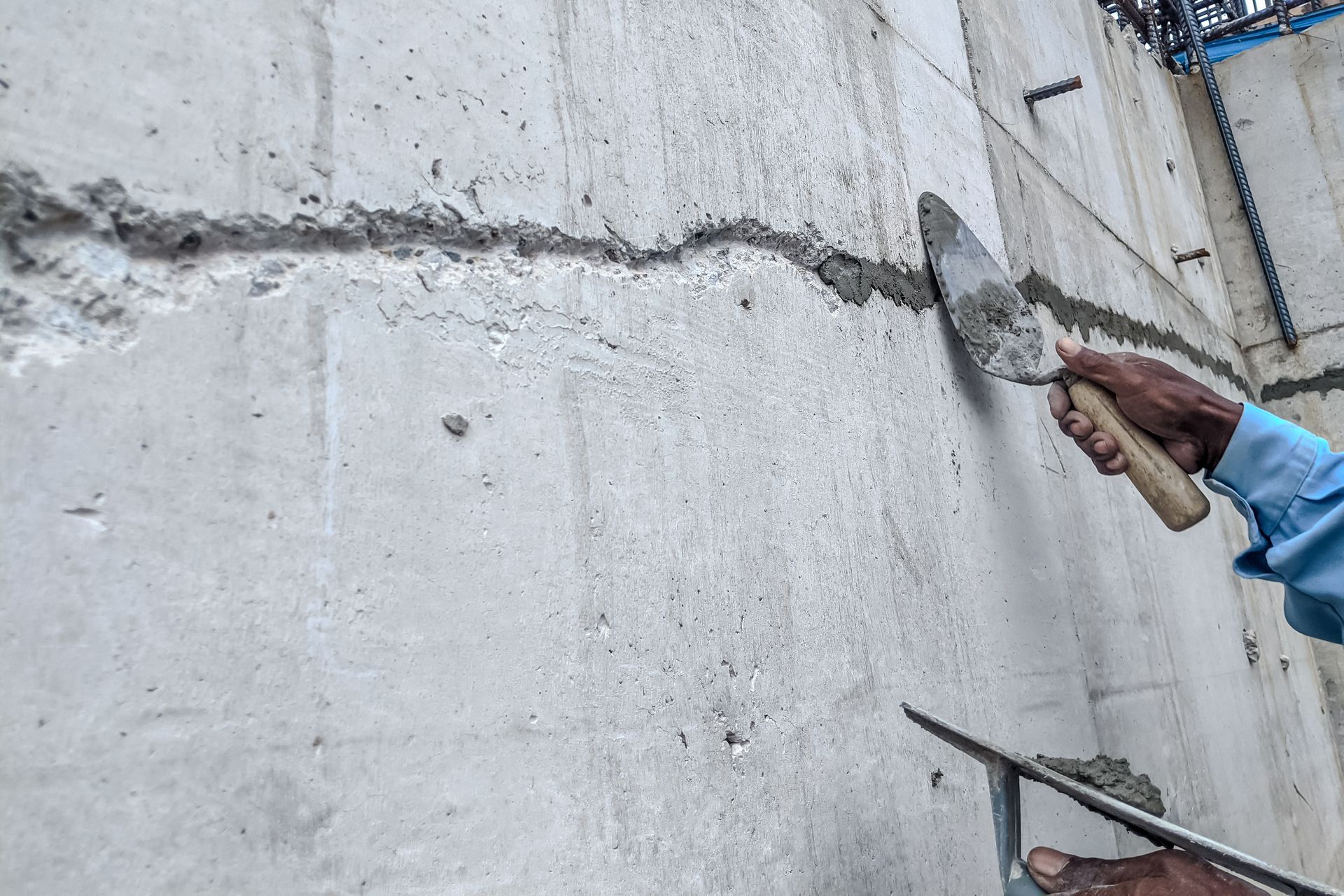 Worker applying plaster to crack in concrete wall with trowel