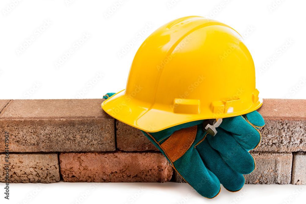 Yellow hard hat and protective work gloves, symbolizing construction safety.