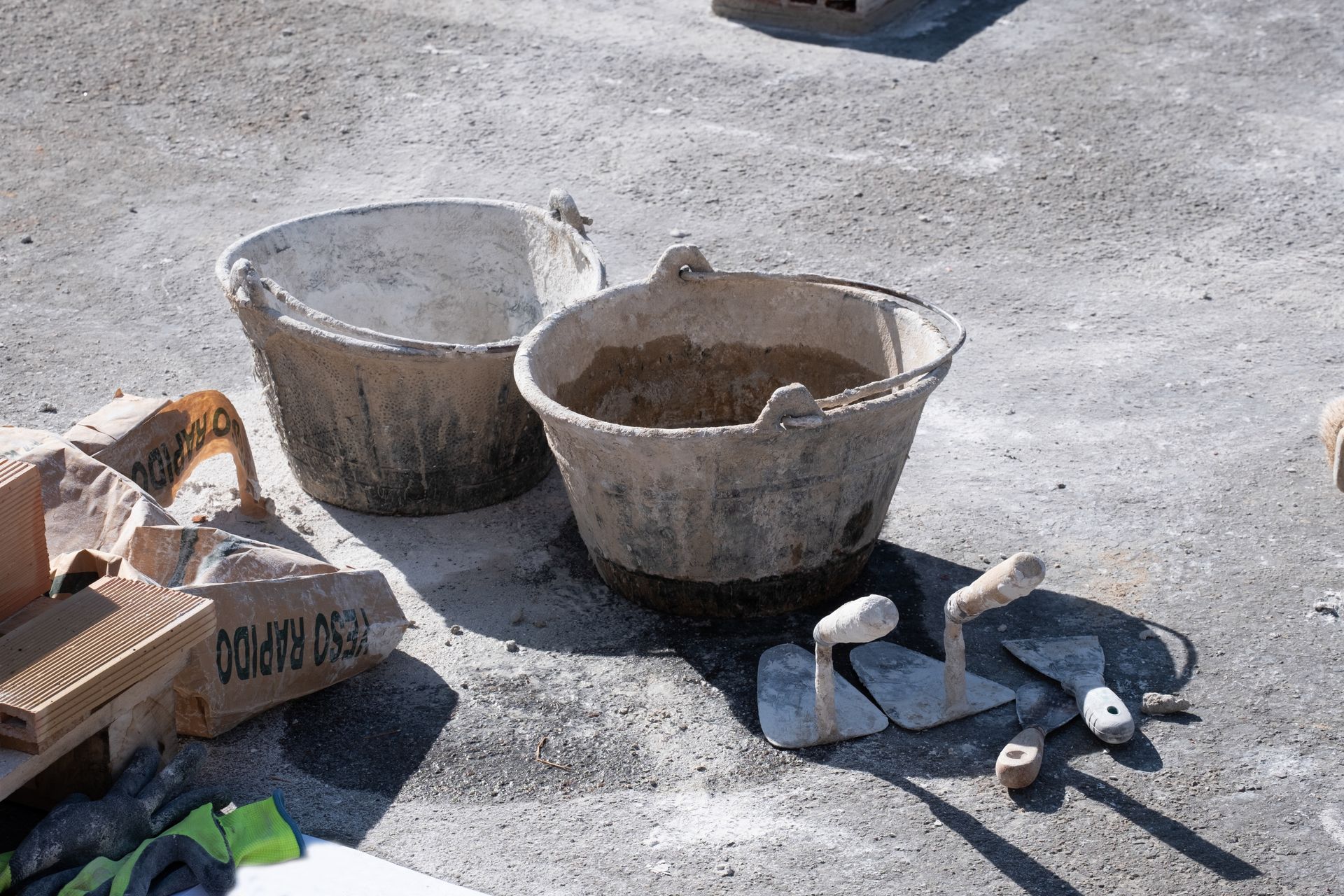 Masonry tools and mixing buckets arranged on a job site for concrete and mortar work. Masonry tools and mixing buckets arranged on a job site for concrete and mortar work.