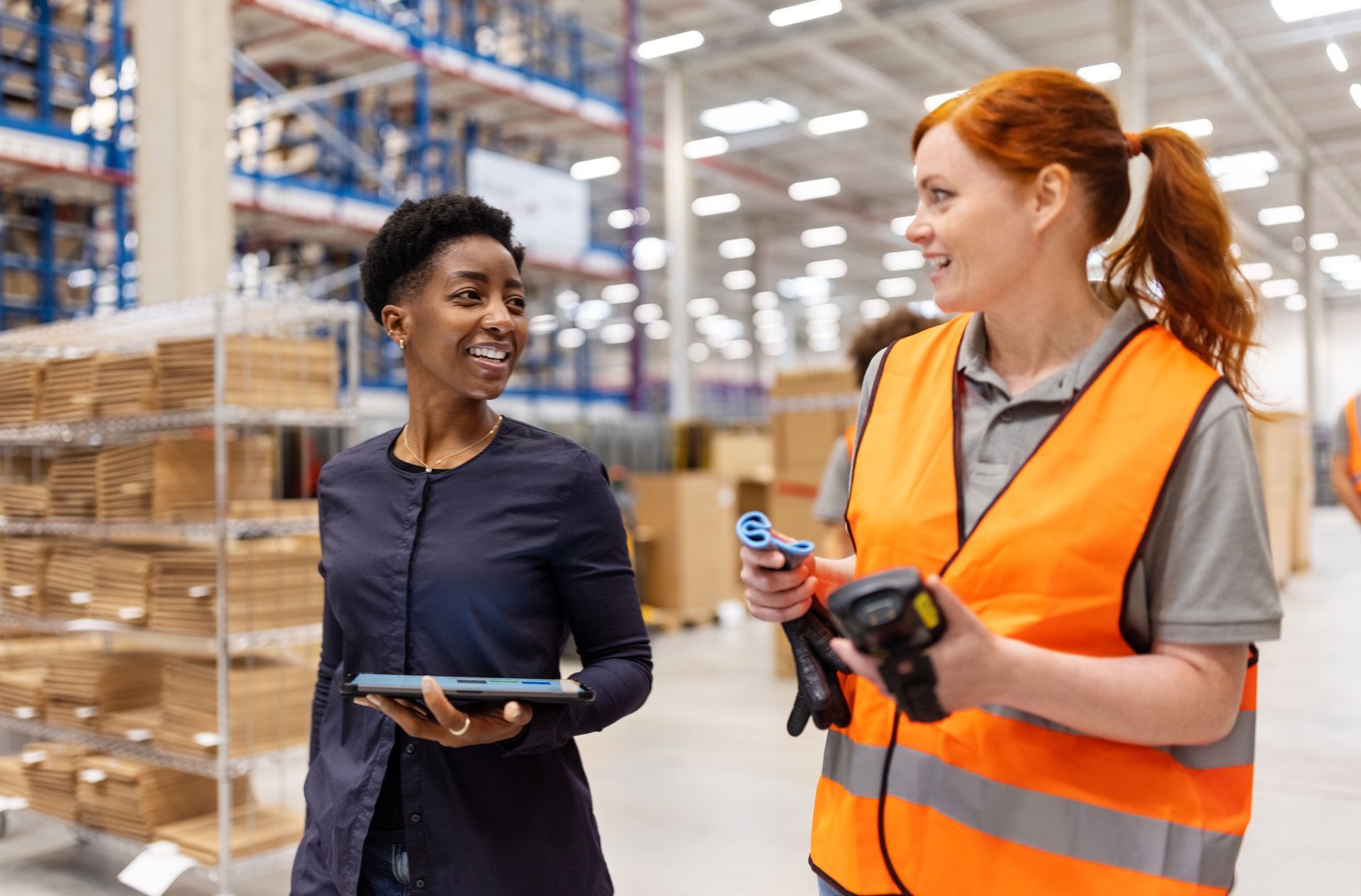 Two Warehouse Workers Conversing And Smiling