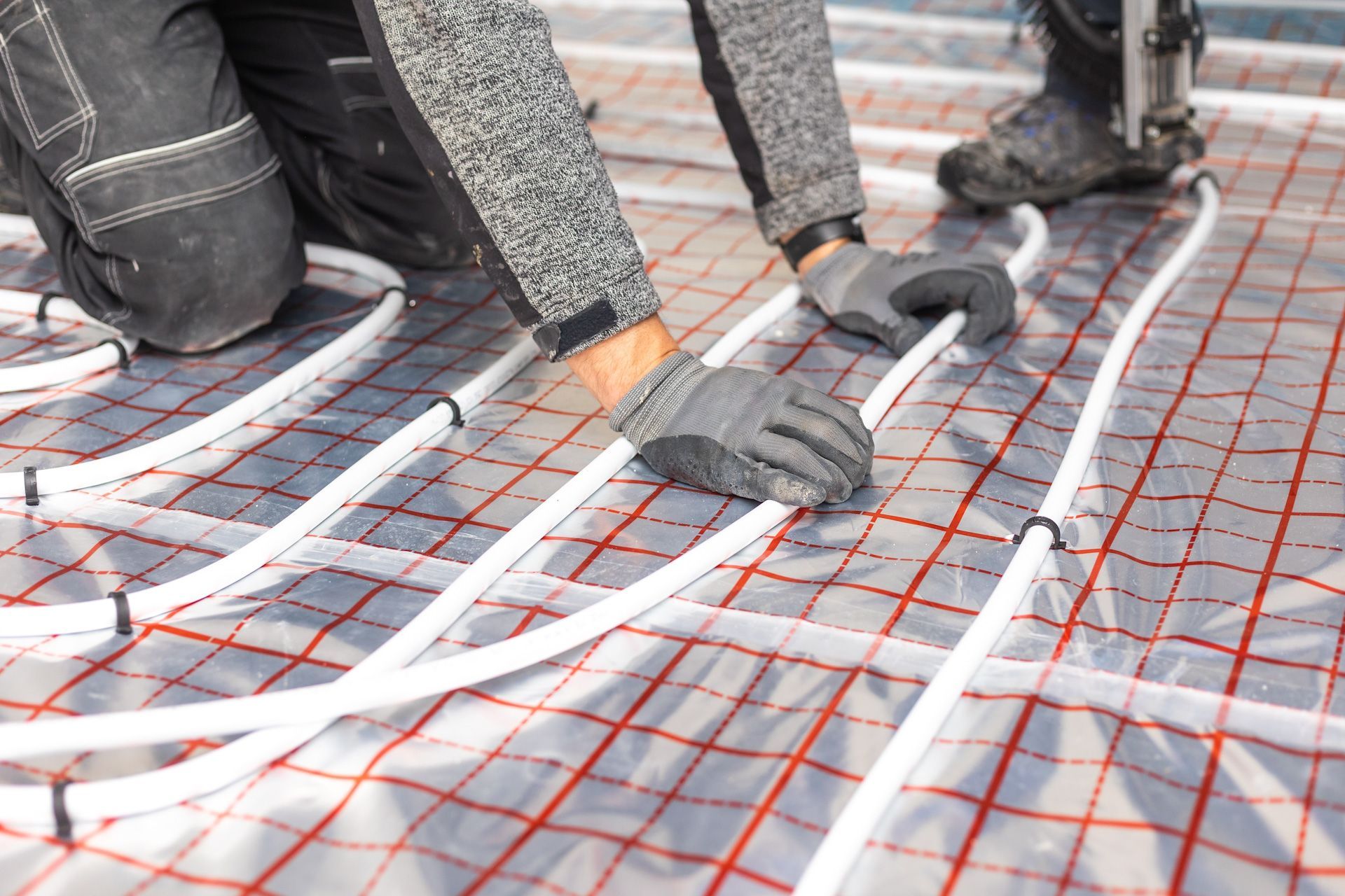 A man is installing underfloor heating pipes on the floor.