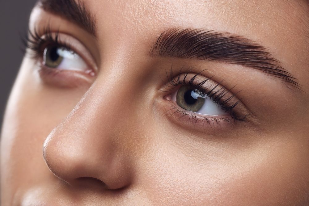 Close-up of a face with well-groomed eyebrows and blue eyes looking upward