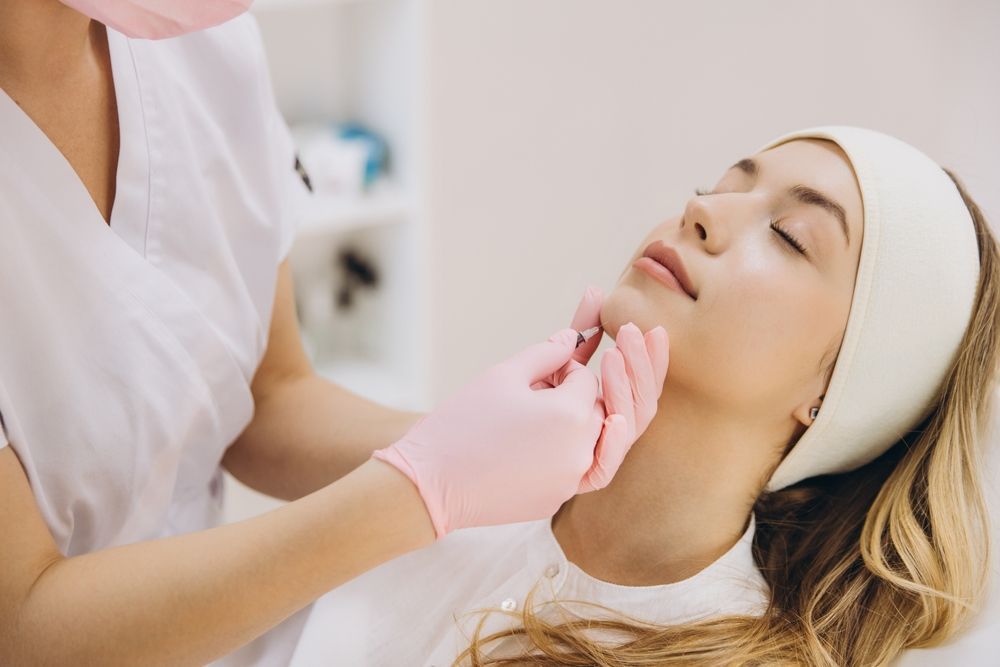 Cosmetic treatment with gloved hands examining a woman’s chin and jawline in a spa setting