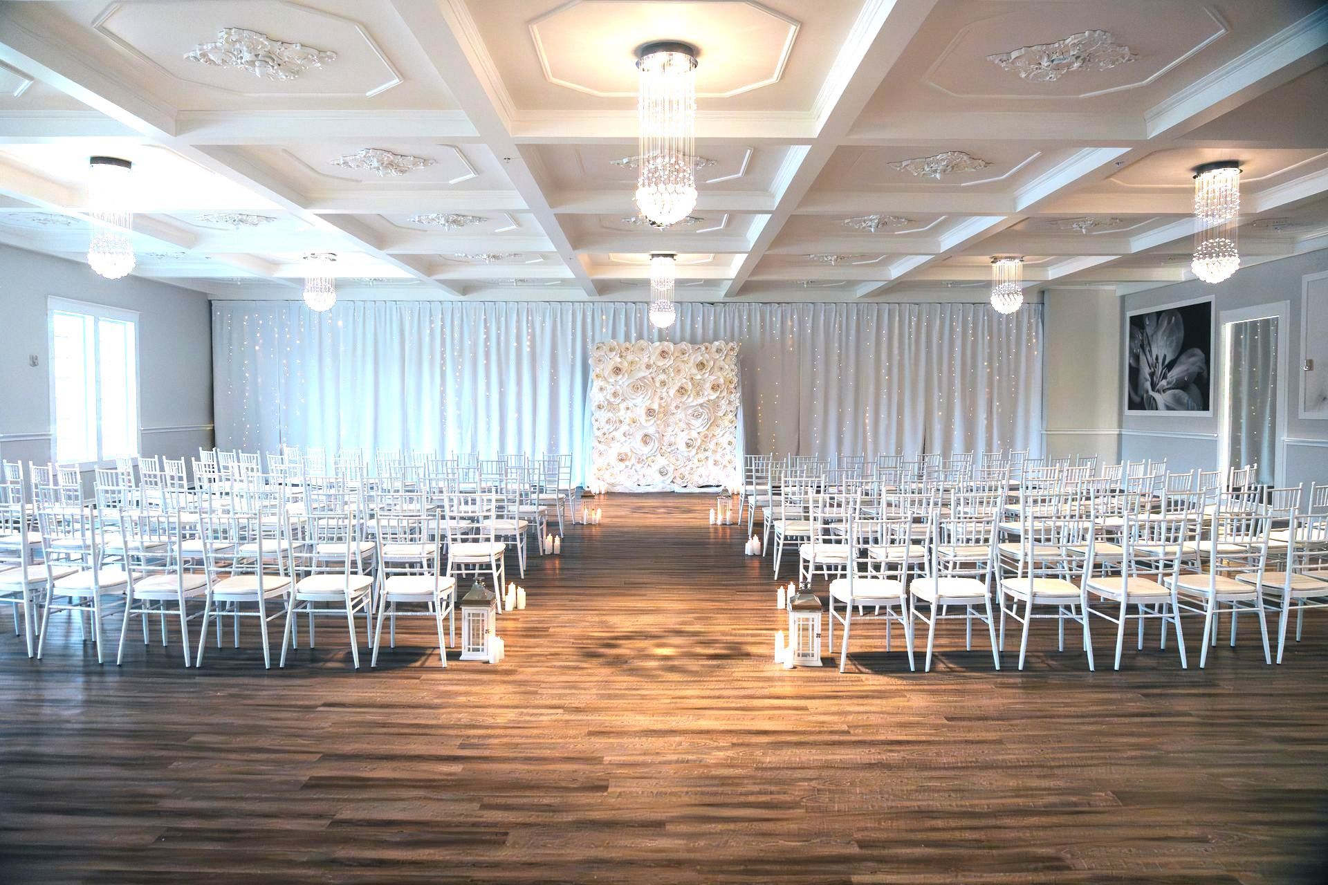 A large room filled with rows of white chairs and a stage.