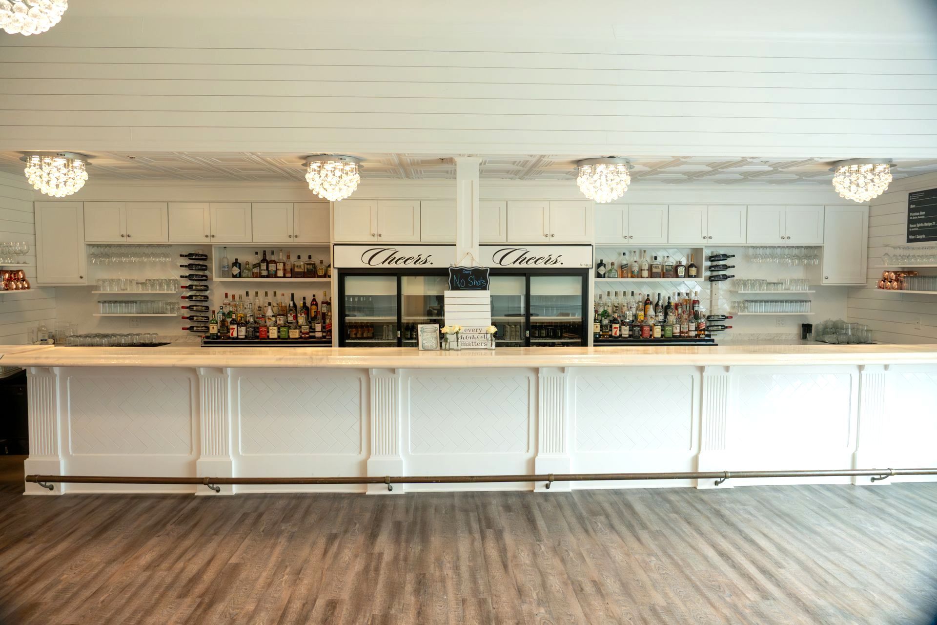 A long white bar in a room with a wooden floor.