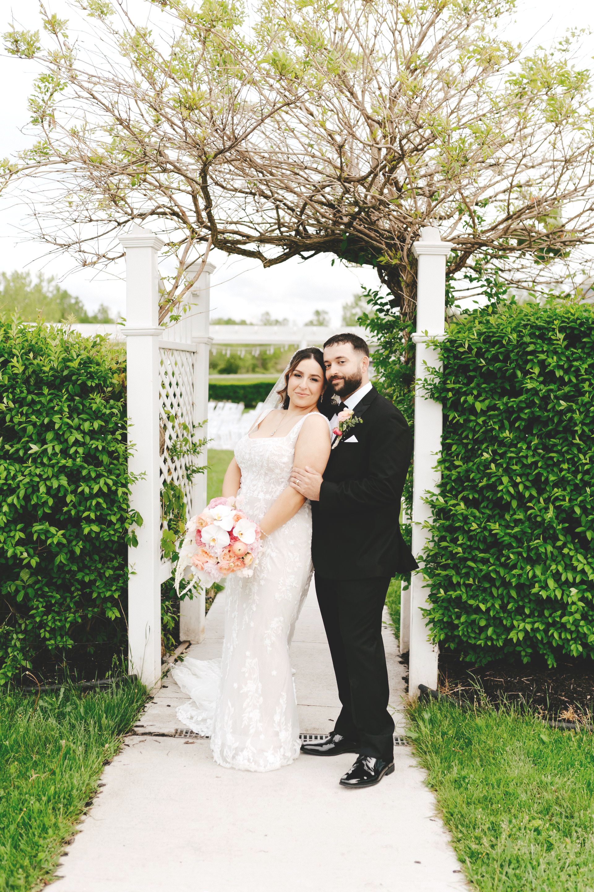 A bride and groom are kissing under a white archway.