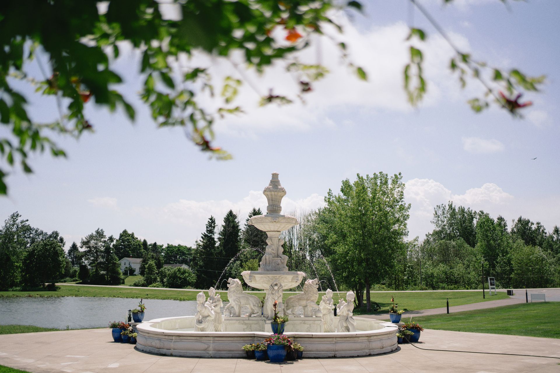 A fountain is sitting in the middle of a park next to a lake.
