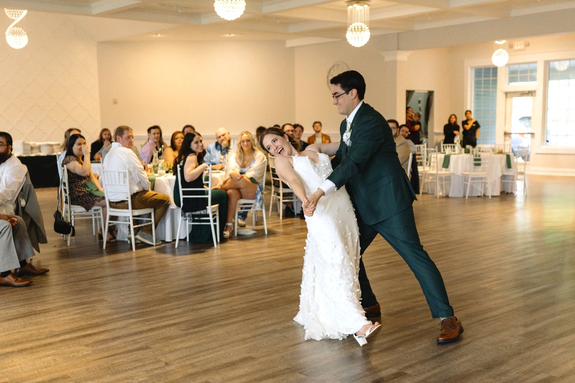 A bride and groom are dancing in front of a crowd at their wedding reception.