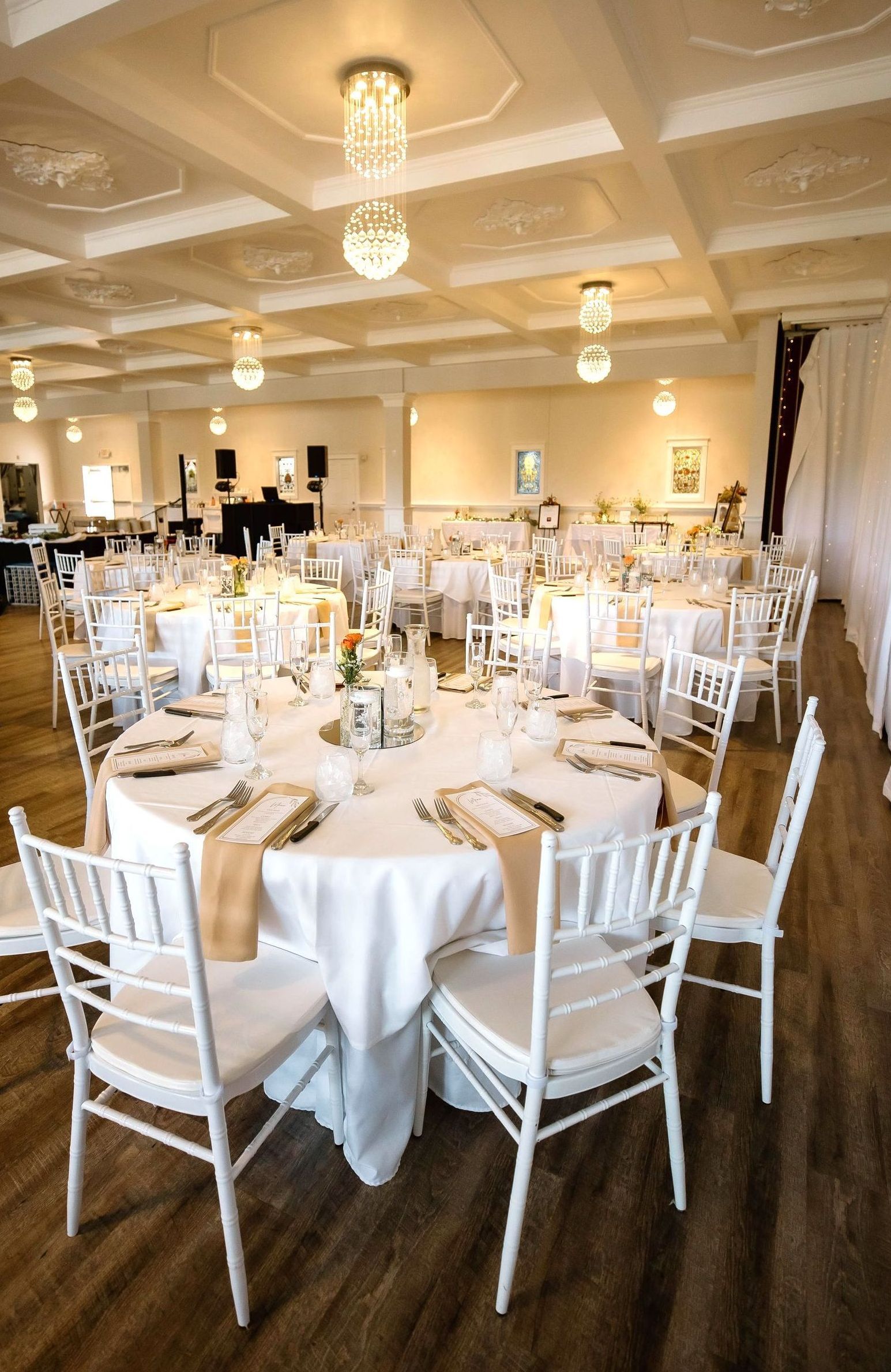 A large room filled with tables and chairs set up for a wedding reception.