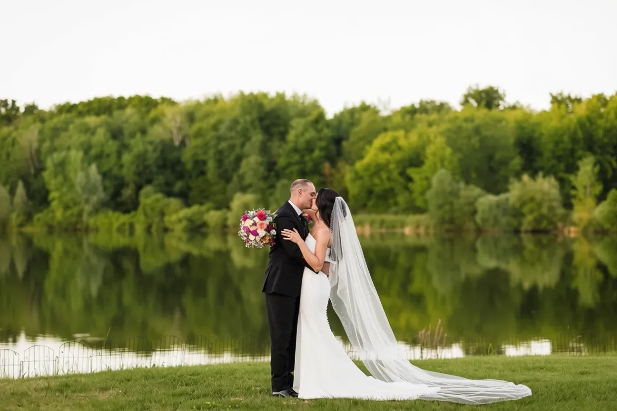 A bride and groom are posing for a picture in front of a lake.