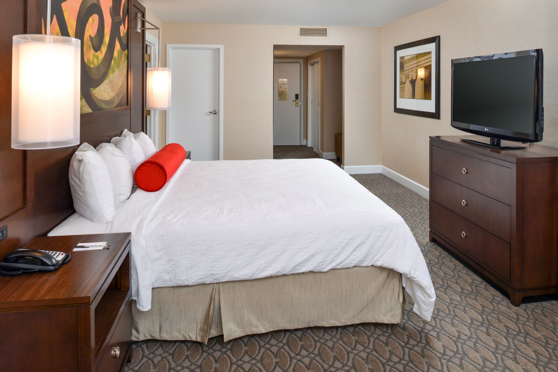 A hotel room with a king size bed and a flat screen tv