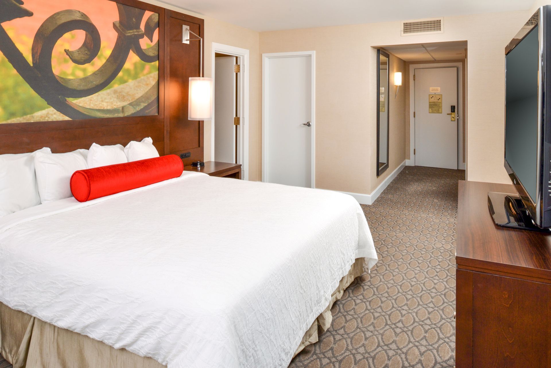 A hotel room with a king size bed and a flat screen tv