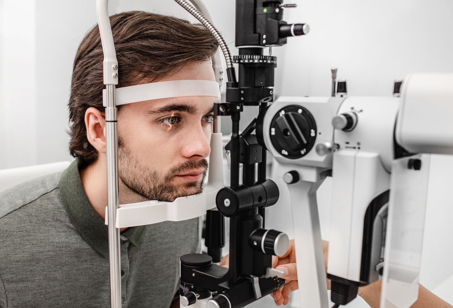 Person using a slit lamp eye exam machine in a clinical setting