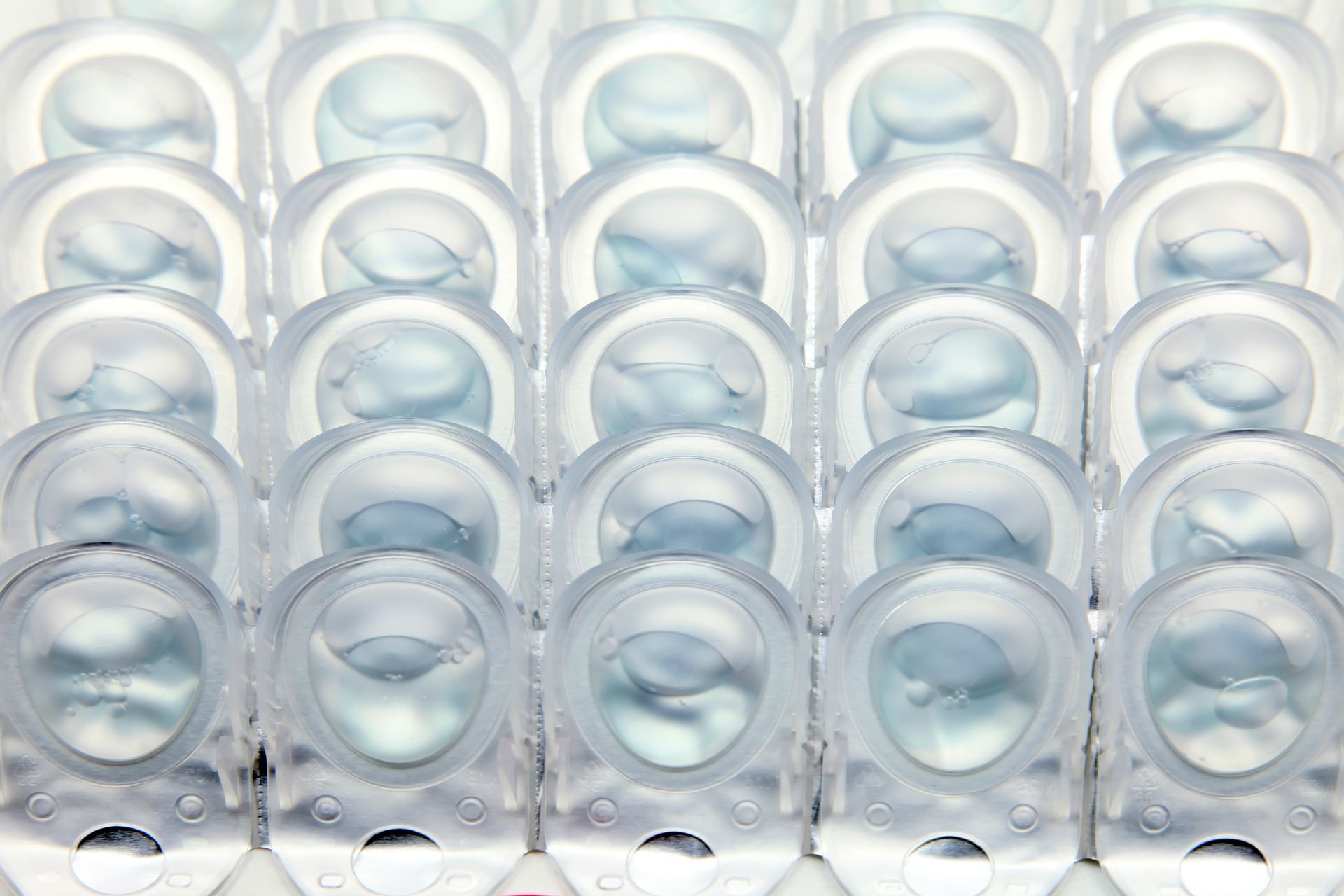 Rows of translucent glass tumblers arranged in a grid on a light surface