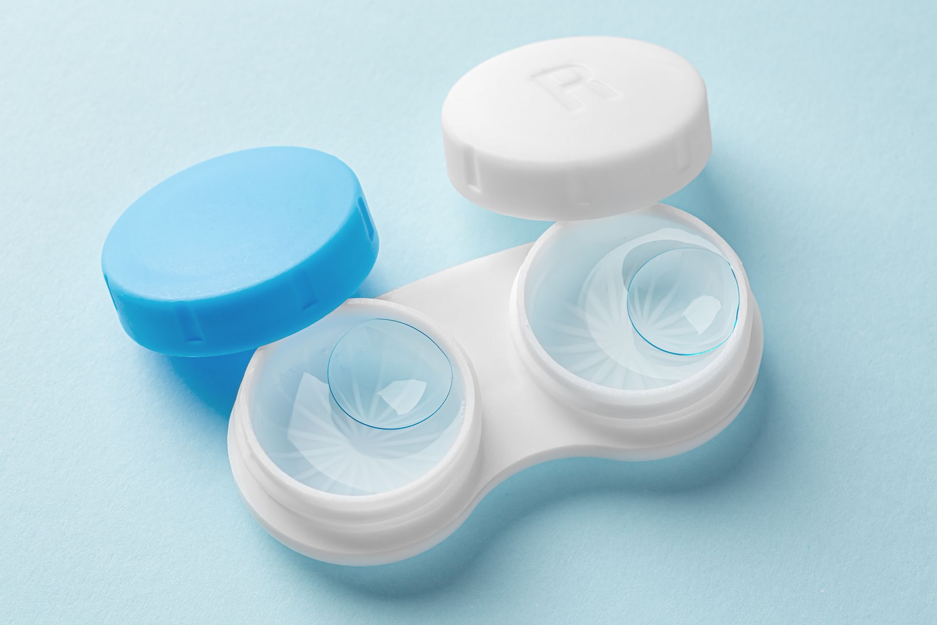 Blue and white contact lens case with two open lens compartments and a blue cap