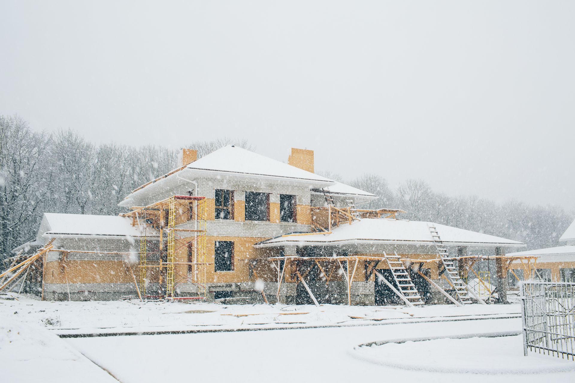 Snow-covered two-story house with lit windows during a heavy snowfall