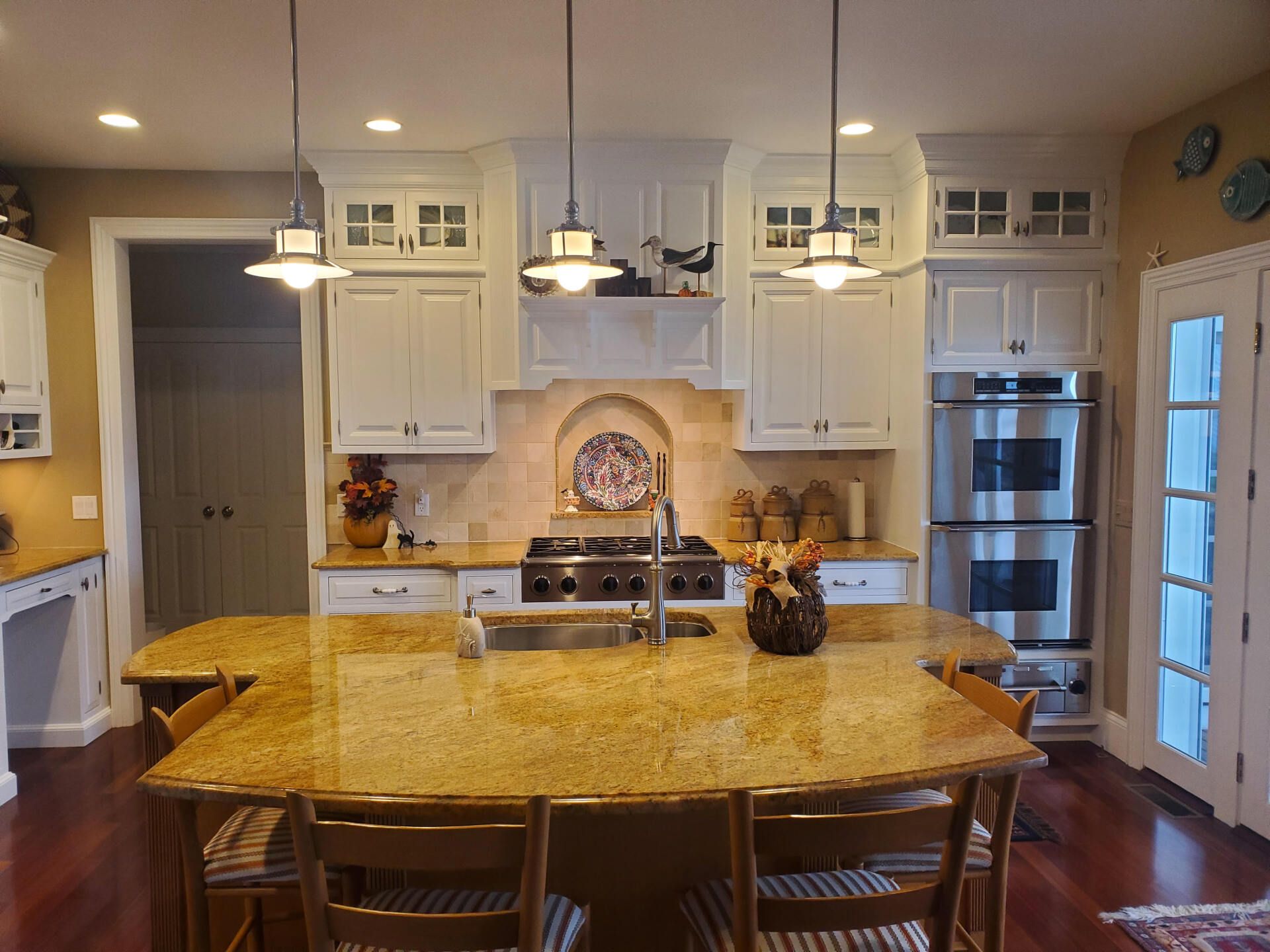 Kitchen with light cabinets, granite island, stainless steel appliances, and pendant lights.