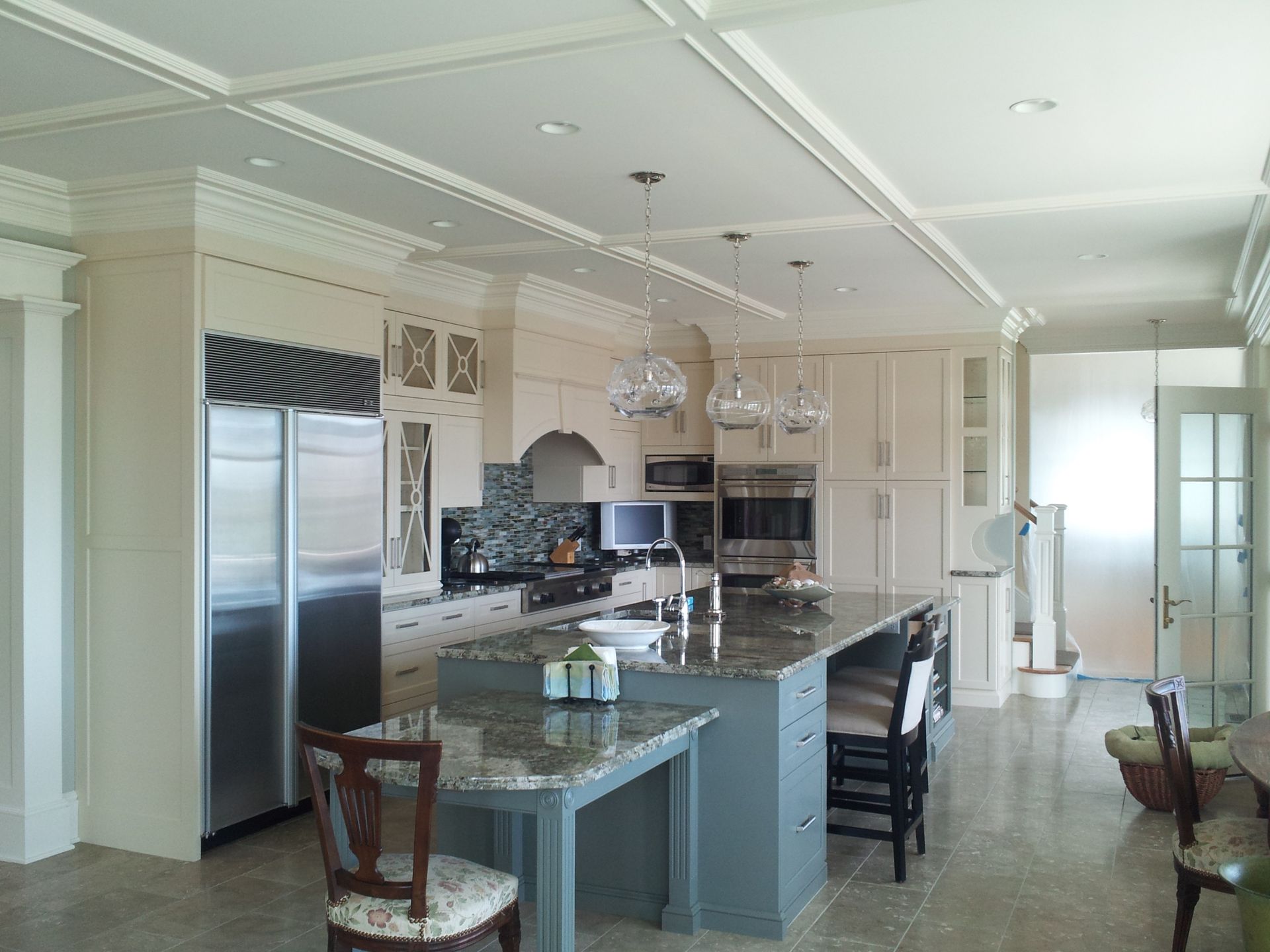 Kitchen with cream cabinets, blue island, granite countertops, stainless steel appliances, and tile floor.